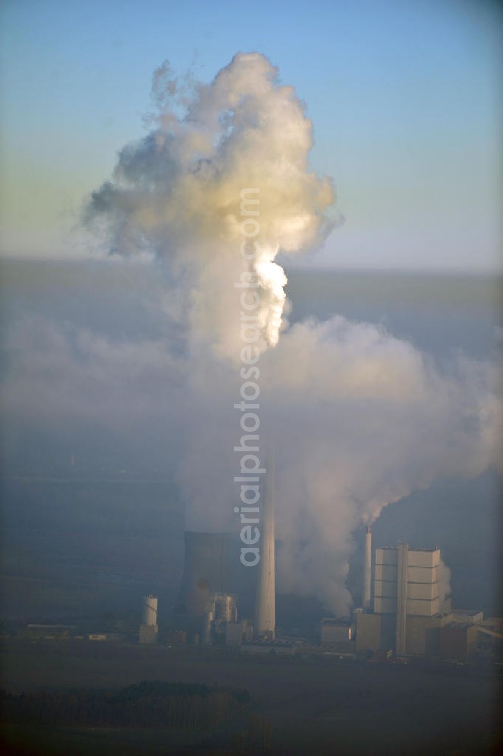 Aerial photograph Schöningen - Weithin sichtbare Abgas- und Rauchwolken der Türme des Kraftwerk Buschhaus , einem Braunkohlekraftwerk im Helmstedter Revier, nahe der Ortschaft Schöningen. Das Kraftwerk der E.ON Kraftwerke GmbH wurde Ende der 1970er-Jahre geplant. Der neue Kraftwerksbau schuf zusätzliche Arbeitsplätze im Kohlebergbau und in der Verstromung. Das Kraftwerk sollte mit der schwefelhaltigen Salzkohle der Umgebung betrieben werden. Für die benötigte Menge wurde eigens ein neuer Tagebau, der Tagebau Schöningen, aufgefahren. Das Kraftwerk verfügt über einen 307 Meter hohen Schornstein, der der höchste in Betrieb befindliche Industrieschornstein in Deutschland ist. Highly visible exhaust and smoke of the towers of the power plant bush house, a brown coal power plant in the Helmstedt area, near the village of Schöningen.