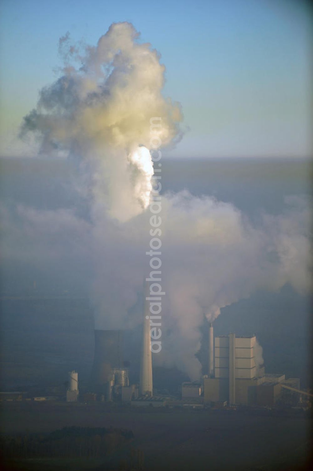 Schöningen from above - Weithin sichtbare Abgas- und Rauchwolken der Türme des Kraftwerk Buschhaus , einem Braunkohlekraftwerk im Helmstedter Revier, nahe der Ortschaft Schöningen. Das Kraftwerk der E.ON Kraftwerke GmbH wurde Ende der 1970er-Jahre geplant. Der neue Kraftwerksbau schuf zusätzliche Arbeitsplätze im Kohlebergbau und in der Verstromung. Das Kraftwerk sollte mit der schwefelhaltigen Salzkohle der Umgebung betrieben werden. Für die benötigte Menge wurde eigens ein neuer Tagebau, der Tagebau Schöningen, aufgefahren. Das Kraftwerk verfügt über einen 307 Meter hohen Schornstein, der der höchste in Betrieb befindliche Industrieschornstein in Deutschland ist. Highly visible exhaust and smoke of the towers of the power plant bush house, a brown coal power plant in the Helmstedt area, near the village of Schöningen.