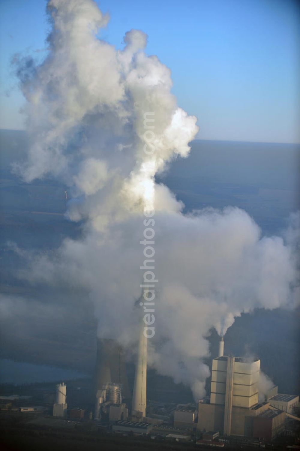 Aerial photograph Schöningen - Weithin sichtbare Abgas- und Rauchwolken der Türme des Kraftwerk Buschhaus , einem Braunkohlekraftwerk im Helmstedter Revier, nahe der Ortschaft Schöningen. Das Kraftwerk der E.ON Kraftwerke GmbH wurde Ende der 1970er-Jahre geplant. Der neue Kraftwerksbau schuf zusätzliche Arbeitsplätze im Kohlebergbau und in der Verstromung. Das Kraftwerk sollte mit der schwefelhaltigen Salzkohle der Umgebung betrieben werden. Für die benötigte Menge wurde eigens ein neuer Tagebau, der Tagebau Schöningen, aufgefahren. Das Kraftwerk verfügt über einen 307 Meter hohen Schornstein, der der höchste in Betrieb befindliche Industrieschornstein in Deutschland ist. Highly visible exhaust and smoke of the towers of the power plant bush house, a brown coal power plant in the Helmstedt area, near the village of Schöningen.