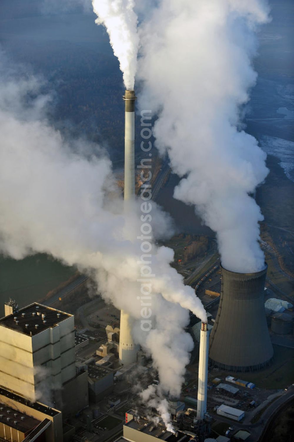 Schöningen from the bird's eye view: Weithin sichtbare Abgas- und Rauchwolken der Türme des Kraftwerk Buschhaus , einem Braunkohlekraftwerk im Helmstedter Revier, nahe der Ortschaft Schöningen. Das Kraftwerk der E.ON Kraftwerke GmbH wurde Ende der 1970er-Jahre geplant. Der neue Kraftwerksbau schuf zusätzliche Arbeitsplätze im Kohlebergbau und in der Verstromung. Das Kraftwerk sollte mit der schwefelhaltigen Salzkohle der Umgebung betrieben werden. Für die benötigte Menge wurde eigens ein neuer Tagebau, der Tagebau Schöningen, aufgefahren. Das Kraftwerk verfügt über einen 307 Meter hohen Schornstein, der der höchste in Betrieb befindliche Industrieschornstein in Deutschland ist. Highly visible exhaust and smoke of the towers of the power plant bush house, a brown coal power plant in the Helmstedt area, near the village of Schöningen.