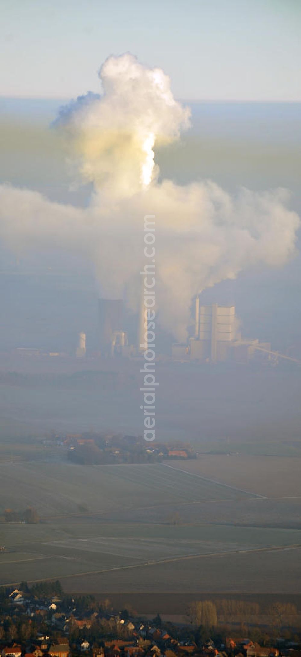 Aerial image Schöningen - Weithin sichtbare Abgas- und Rauchwolken der Türme des Kraftwerk Buschhaus , einem Braunkohlekraftwerk im Helmstedter Revier, nahe der Ortschaft Schöningen. Das Kraftwerk der E.ON Kraftwerke GmbH wurde Ende der 1970er-Jahre geplant. Der neue Kraftwerksbau schuf zusätzliche Arbeitsplätze im Kohlebergbau und in der Verstromung. Das Kraftwerk sollte mit der schwefelhaltigen Salzkohle der Umgebung betrieben werden. Für die benötigte Menge wurde eigens ein neuer Tagebau, der Tagebau Schöningen, aufgefahren. Das Kraftwerk verfügt über einen 307 Meter hohen Schornstein, der der höchste in Betrieb befindliche Industrieschornstein in Deutschland ist. Highly visible exhaust and smoke of the towers of the power plant bush house, a brown coal power plant in the Helmstedt area, near the village of Schöningen.