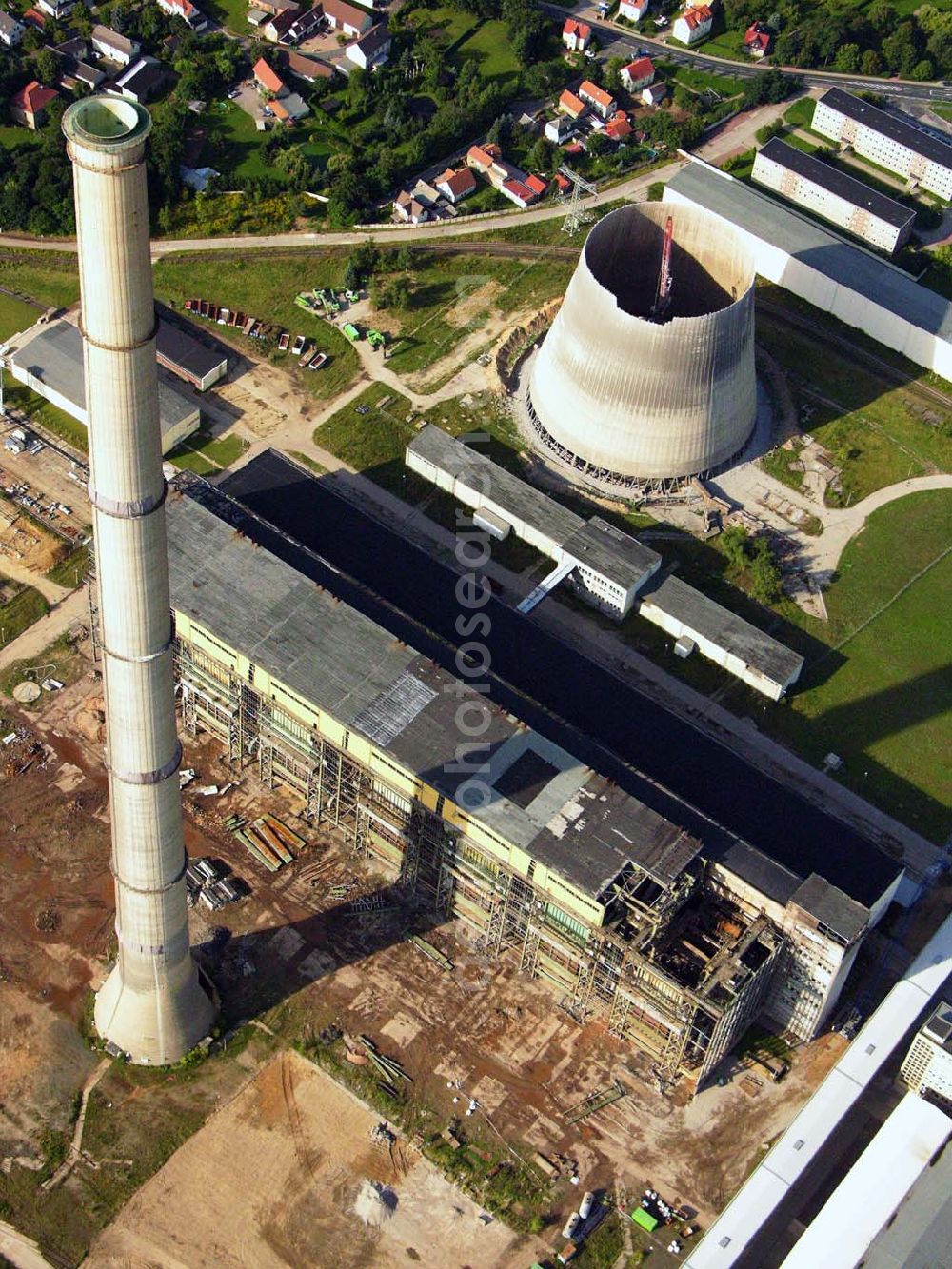 Neukieritzsch from the bird's eye view: 27.08.2005 Neukieritzsch; Durch die nach 1990 gültigen Umweltgesetze entschieden die Eigentümer, dass eine Nachrüstung mit moderner Umwelttechnik aus technischen wie wirtschaftlichen Gründen nicht realisierbar ist. Deshalb erfolgte mit der Inbetriebnahme der beiden Neubau-Blöcke die schrittweise Stilllegung und der Rückbau des Altkraftwerkes Lippendorf. Der erste Kühlturm wurde am 6. Dezember 1997 gesprengt, der zweite wurde 2005 mittels hydraulischer Abbruchzange rückgebaut. Am 27. August 2005 wurde der Schornstein gesprengt, am 5. September 2005 folgte das Kesselhaus.