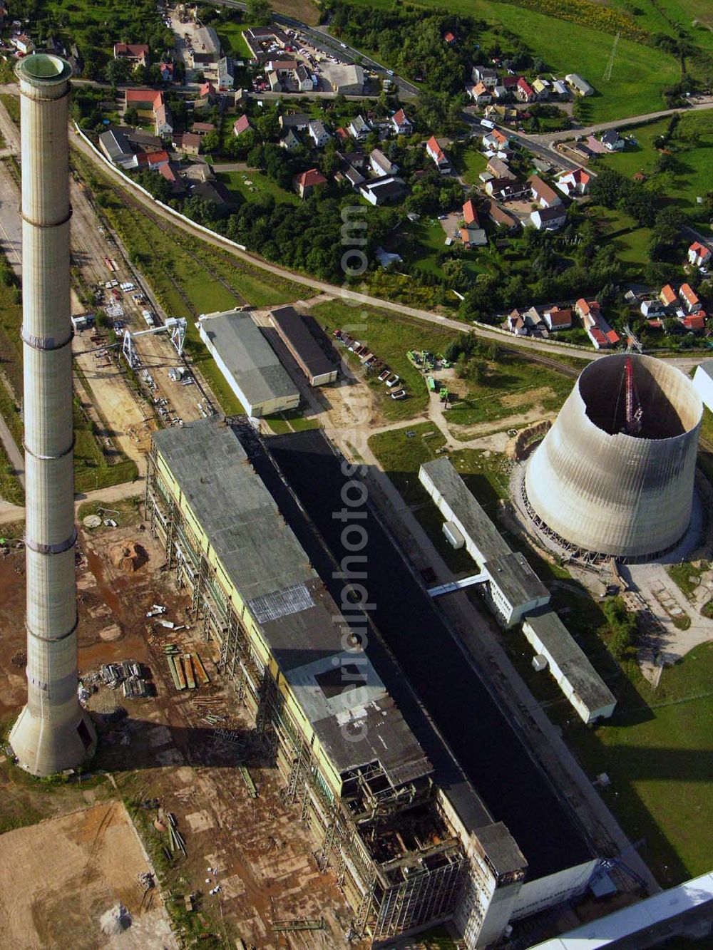 Aerial image Neukieritzsch - 27.08.2005 Neukieritzsch; Durch die nach 1990 gültigen Umweltgesetze entschieden die Eigentümer, dass eine Nachrüstung mit moderner Umwelttechnik aus technischen wie wirtschaftlichen Gründen nicht realisierbar ist. Deshalb erfolgte mit der Inbetriebnahme der beiden Neubau-Blöcke die schrittweise Stilllegung und der Rückbau des Altkraftwerkes Lippendorf. Der erste Kühlturm wurde am 6. Dezember 1997 gesprengt, der zweite wurde 2005 mittels hydraulischer Abbruchzange rückgebaut. Am 27. August 2005 wurde der Schornstein gesprengt, am 5. September 2005 folgte das Kesselhaus.