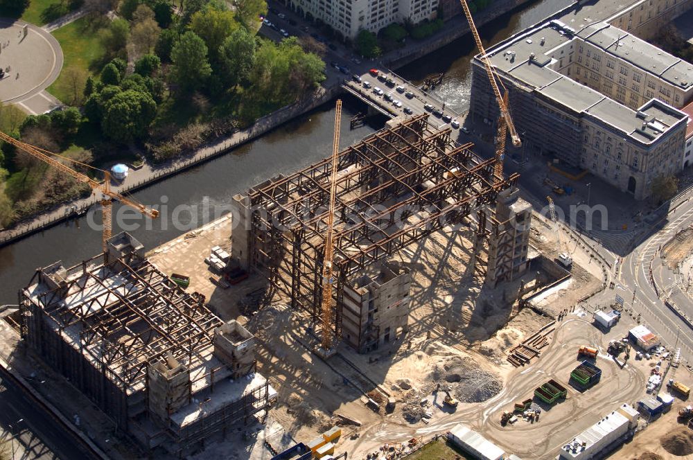 Berlin from above - Blick auf den Abriss des Palast der Republik in Mitte.Der Rückbau des Palastes der Republik verschob sich immer wieder. Am 19. Januar 2006 beschloss der Deutsche Bundestag, Anträgen der Grünen und der Linkspartei zur Verschiebung des Abrisses bzw. zur Erhaltung des Bauwerks nicht stattzugeben.Nach Terminen im Frühjahr 2005 und im Oktober 2005 wird das Gebäude seit Februar 2006 langsam mithilfe von fünf Kränen zurückgebaut. Von einer Sprengung des Gebäudes wurde abgesehen, weil Beschädigungen umliegender Gebäude durch den Auftrieb der Bodenwanne und das dadurch bedingte Absinken des Grundwasserspiegels befürchtet wurden. Stattdessen wird das abgetragene Material gemessen und im gleichen Maß dann mit Wasser versetzter Sand in die Bodenwanne geleitet.Die Abrissarbeiten sollten ursprünglich Mitte 2007 abgeschlossen sein. Nachdem im Laufe der Arbeiten an mehreren Stellen neues Asbest gefunden wurde und sich der Abriss dadurch stark verlangsamte, wird mit Ende 2008 als frühestes Ende kalkuliert. Die Zusatzkosten in Höhe von bislang 9,9 Mio. Euro muss der Bund übernehmen.Nach der vollständigen Abtragung soll vorübergehend eine Grünfläche über der verbleibenden Bodenwanne entstehen.