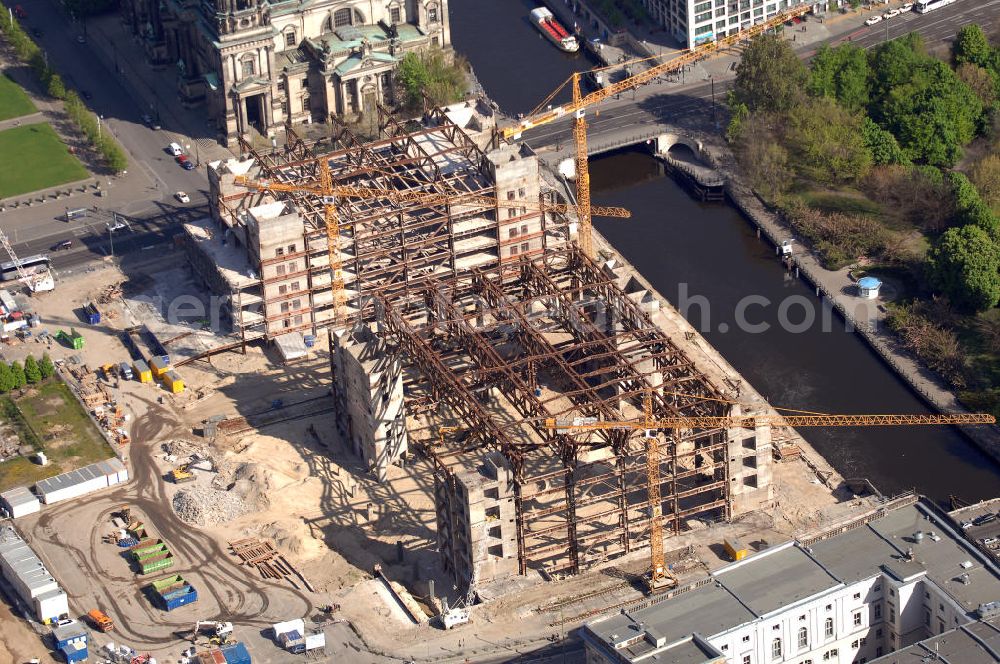 Aerial image Berlin - Blick auf den Abriss des Palast der Republik in Mitte.Der Rückbau des Palastes der Republik verschob sich immer wieder. Am 19. Januar 2006 beschloss der Deutsche Bundestag, Anträgen der Grünen und der Linkspartei zur Verschiebung des Abrisses bzw. zur Erhaltung des Bauwerks nicht stattzugeben.Nach Terminen im Frühjahr 2005 und im Oktober 2005 wird das Gebäude seit Februar 2006 langsam mithilfe von fünf Kränen zurückgebaut. Von einer Sprengung des Gebäudes wurde abgesehen, weil Beschädigungen umliegender Gebäude durch den Auftrieb der Bodenwanne und das dadurch bedingte Absinken des Grundwasserspiegels befürchtet wurden. Stattdessen wird das abgetragene Material gemessen und im gleichen Maß dann mit Wasser versetzter Sand in die Bodenwanne geleitet.Die Abrissarbeiten sollten ursprünglich Mitte 2007 abgeschlossen sein. Nachdem im Laufe der Arbeiten an mehreren Stellen neues Asbest gefunden wurde und sich der Abriss dadurch stark verlangsamte, wird mit Ende 2008 als frühestes Ende kalkuliert. Die Zusatzkosten in Höhe von bislang 9,9 Mio. Euro muss der Bund übernehmen.Nach der vollständigen Abtragung soll vorübergehend eine Grünfläche über der verbleibenden Bodenwanne entstehen.