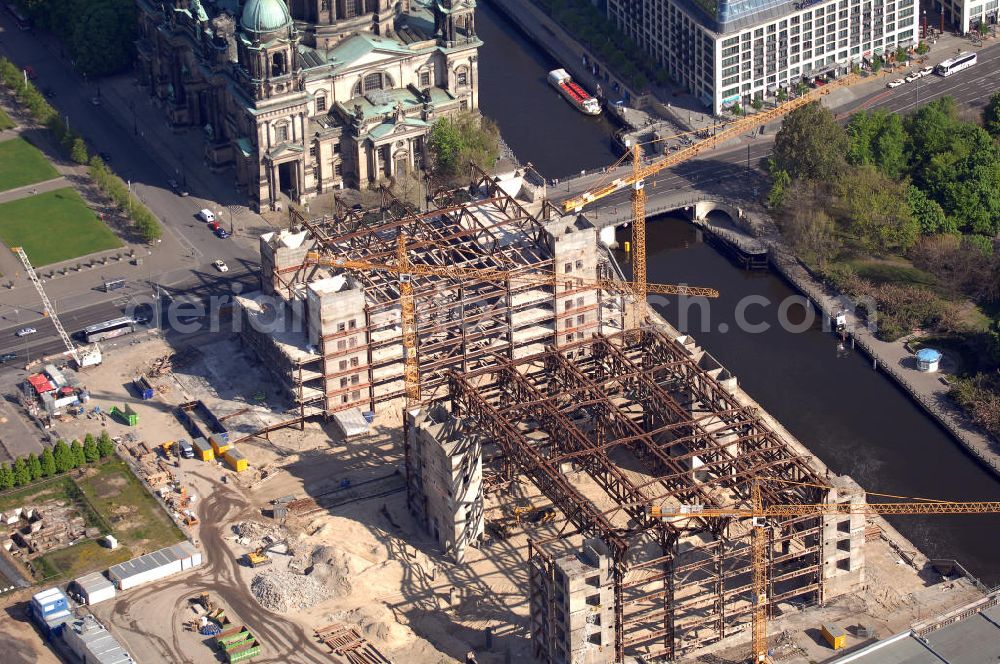 Aerial photograph Berlin - Blick auf den Abriss des Palast der Republik in Mitte.Der Rückbau des Palastes der Republik verschob sich immer wieder. Am 19. Januar 2006 beschloss der Deutsche Bundestag, Anträgen der Grünen und der Linkspartei zur Verschiebung des Abrisses bzw. zur Erhaltung des Bauwerks nicht stattzugeben.Nach Terminen im Frühjahr 2005 und im Oktober 2005 wird das Gebäude seit Februar 2006 langsam mithilfe von fünf Kränen zurückgebaut. Von einer Sprengung des Gebäudes wurde abgesehen, weil Beschädigungen umliegender Gebäude durch den Auftrieb der Bodenwanne und das dadurch bedingte Absinken des Grundwasserspiegels befürchtet wurden. Stattdessen wird das abgetragene Material gemessen und im gleichen Maß dann mit Wasser versetzter Sand in die Bodenwanne geleitet.Die Abrissarbeiten sollten ursprünglich Mitte 2007 abgeschlossen sein. Nachdem im Laufe der Arbeiten an mehreren Stellen neues Asbest gefunden wurde und sich der Abriss dadurch stark verlangsamte, wird mit Ende 2008 als frühestes Ende kalkuliert. Die Zusatzkosten in Höhe von bislang 9,9 Mio. Euro muss der Bund übernehmen.Nach der vollständigen Abtragung soll vorübergehend eine Grünfläche über der verbleibenden Bodenwanne entstehen.