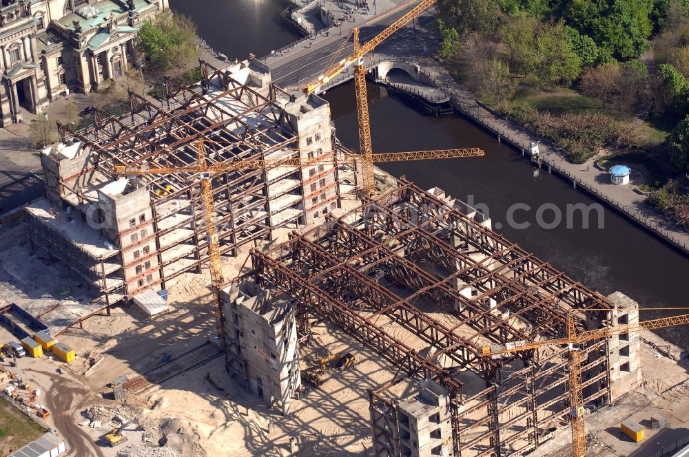 Berlin from above - Blick auf den Abriss des Palast der Republik in Mitte.Der Rückbau des Palastes der Republik verschob sich immer wieder. Am 19. Januar 2006 beschloss der Deutsche Bundestag, Anträgen der Grünen und der Linkspartei zur Verschiebung des Abrisses bzw. zur Erhaltung des Bauwerks nicht stattzugeben.Nach Terminen im Frühjahr 2005 und im Oktober 2005 wird das Gebäude seit Februar 2006 langsam mithilfe von fünf Kränen zurückgebaut. Von einer Sprengung des Gebäudes wurde abgesehen, weil Beschädigungen umliegender Gebäude durch den Auftrieb der Bodenwanne und das dadurch bedingte Absinken des Grundwasserspiegels befürchtet wurden. Stattdessen wird das abgetragene Material gemessen und im gleichen Maß dann mit Wasser versetzter Sand in die Bodenwanne geleitet.Die Abrissarbeiten sollten ursprünglich Mitte 2007 abgeschlossen sein. Nachdem im Laufe der Arbeiten an mehreren Stellen neues Asbest gefunden wurde und sich der Abriss dadurch stark verlangsamte, wird mit Ende 2008 als frühestes Ende kalkuliert. Die Zusatzkosten in Höhe von bislang 9,9 Mio. Euro muss der Bund übernehmen.Nach der vollständigen Abtragung soll vorübergehend eine Grünfläche über der verbleibenden Bodenwanne entstehen.