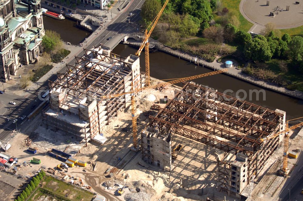 Aerial image Berlin - Blick auf den Abriss des Palast der Republik in Mitte.Der Rückbau des Palastes der Republik verschob sich immer wieder. Am 19. Januar 2006 beschloss der Deutsche Bundestag, Anträgen der Grünen und der Linkspartei zur Verschiebung des Abrisses bzw. zur Erhaltung des Bauwerks nicht stattzugeben.Nach Terminen im Frühjahr 2005 und im Oktober 2005 wird das Gebäude seit Februar 2006 langsam mithilfe von fünf Kränen zurückgebaut. Von einer Sprengung des Gebäudes wurde abgesehen, weil Beschädigungen umliegender Gebäude durch den Auftrieb der Bodenwanne und das dadurch bedingte Absinken des Grundwasserspiegels befürchtet wurden. Stattdessen wird das abgetragene Material gemessen und im gleichen Maß dann mit Wasser versetzter Sand in die Bodenwanne geleitet.Die Abrissarbeiten sollten ursprünglich Mitte 2007 abgeschlossen sein. Nachdem im Laufe der Arbeiten an mehreren Stellen neues Asbest gefunden wurde und sich der Abriss dadurch stark verlangsamte, wird mit Ende 2008 als frühestes Ende kalkuliert. Die Zusatzkosten in Höhe von bislang 9,9 Mio. Euro muss der Bund übernehmen.Nach der vollständigen Abtragung soll vorübergehend eine Grünfläche über der verbleibenden Bodenwanne entstehen.