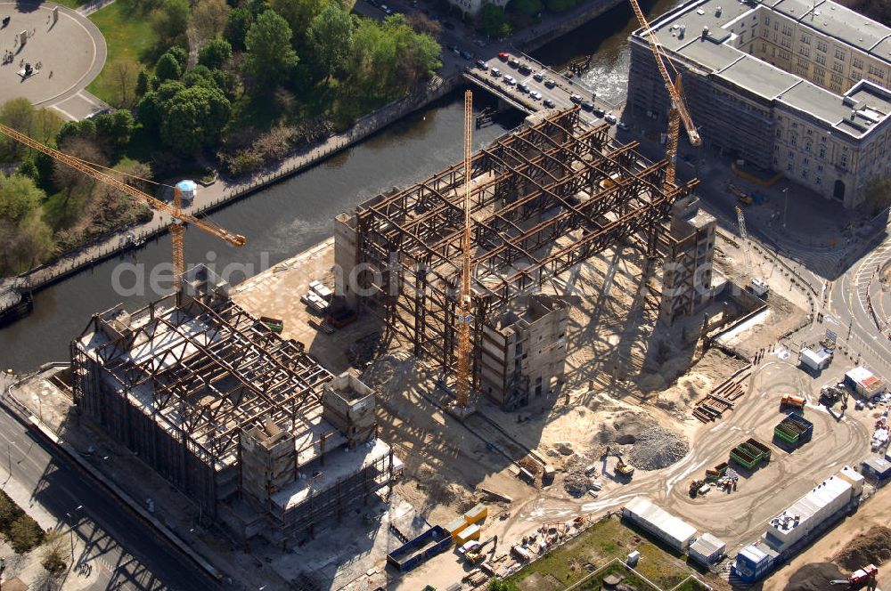 Aerial image Berlin - Blick auf den Abriss des Palast der Republik in Mitte.Der Rückbau des Palastes der Republik verschob sich immer wieder. Am 19. Januar 2006 beschloss der Deutsche Bundestag, Anträgen der Grünen und der Linkspartei zur Verschiebung des Abrisses bzw. zur Erhaltung des Bauwerks nicht stattzugeben.Nach Terminen im Frühjahr 2005 und im Oktober 2005 wird das Gebäude seit Februar 2006 langsam mithilfe von fünf Kränen zurückgebaut. Von einer Sprengung des Gebäudes wurde abgesehen, weil Beschädigungen umliegender Gebäude durch den Auftrieb der Bodenwanne und das dadurch bedingte Absinken des Grundwasserspiegels befürchtet wurden. Stattdessen wird das abgetragene Material gemessen und im gleichen Maß dann mit Wasser versetzter Sand in die Bodenwanne geleitet.Die Abrissarbeiten sollten ursprünglich Mitte 2007 abgeschlossen sein. Nachdem im Laufe der Arbeiten an mehreren Stellen neues Asbest gefunden wurde und sich der Abriss dadurch stark verlangsamte, wird mit Ende 2008 als frühestes Ende kalkuliert. Die Zusatzkosten in Höhe von bislang 9,9 Mio. Euro muss der Bund übernehmen.Nach der vollständigen Abtragung soll vorübergehend eine Grünfläche über der verbleibenden Bodenwanne entstehen.