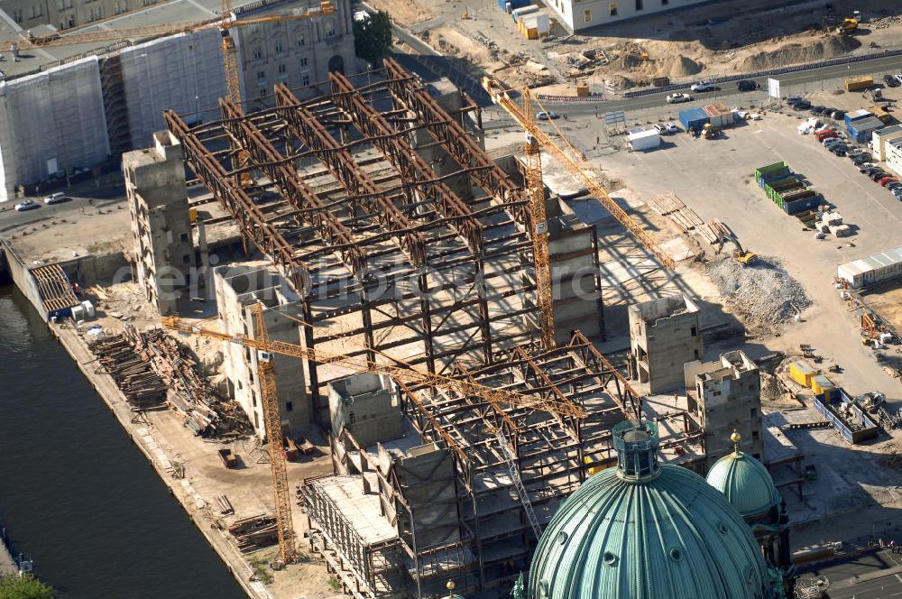 Aerial photograph Berlin - . Seit Februar 2006 wird der Palast langsam mit Hilfe von fünf Kränen abgerissen. Von einer Sprengung des Gebäudes wurde abgesehen, weil Beschädigungen umliegender Häuser durch den Auftrieb der Bodenwanne und das dadurch bedingte Absinken des Grundwasserspiegels befürchtet wurden. Stattdessen wird das abgetragene Material gemessen und dann im gleichen Maß mit Wasser versetzter Sand in die Bodenwanne geleitet. Die Abrissarbeiten sollten ursprünglich Mitte 2007 abgeschlossen sein. Nachdem im Laufe der Arbeiten an mehreren Stellen neuer Asbest gefunden wurde und sich der Abriss dadurch stark verlangsamte, wird mit Ende 2008 als frühestem Ende kalkuliert. Die Zusatzkosten in Höhe von bislang 9,9 Mio. Euro muss der Bund übernehmen. Nach der vollständigen Abtragung soll vorübergehend eine Grünfläche über der verbleibenden Bodenwanne entstehen.