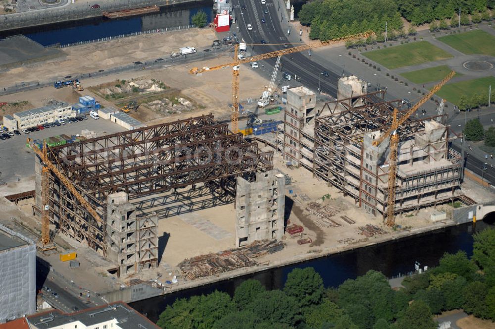 Aerial photograph Berlin - . Seit Februar 2006 wird der Palast langsam mit Hilfe von fünf Kränen abgerissen. Von einer Sprengung des Gebäudes wurde abgesehen, weil Beschädigungen umliegender Häuser durch den Auftrieb der Bodenwanne und das dadurch bedingte Absinken des Grundwasserspiegels befürchtet wurden. Stattdessen wird das abgetragene Material gemessen und dann im gleichen Maß mit Wasser versetzter Sand in die Bodenwanne geleitet. Die Abrissarbeiten sollten ursprünglich Mitte 2007 abgeschlossen sein. Nachdem im Laufe der Arbeiten an mehreren Stellen neuer Asbest gefunden wurde und sich der Abriss dadurch stark verlangsamte, wird mit Ende 2008 als frühestem Ende kalkuliert. Die Zusatzkosten in Höhe von bislang 9,9 Mio. Euro muss der Bund übernehmen. Nach der vollständigen Abtragung soll vorübergehend eine Grünfläche über der verbleibenden Bodenwanne entstehen.