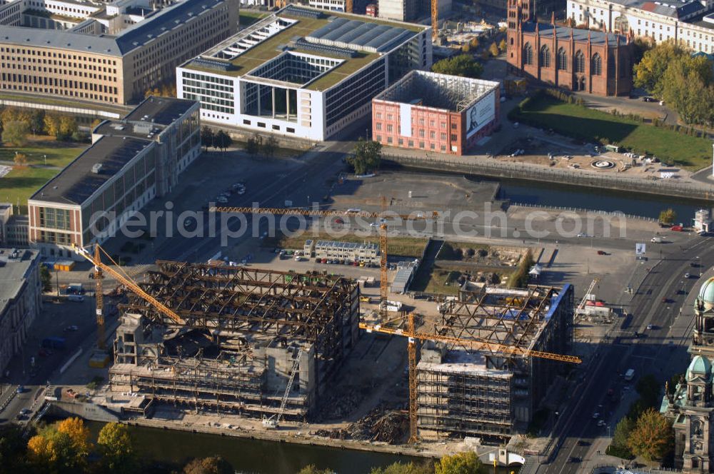 Aerial image Berlin - Blick auf den Abriss des Palast der Republik in Mitte.Der Rückbau des Palastes der Republik verschob sich immer wieder. Am 19. Januar 2006 beschloss der Deutsche Bundestag, Anträgen der Grünen und der Linkspartei zur Verschiebung des Abrisses bzw. zur Erhaltung des Bauwerks nicht stattzugeben.Nach Terminen im Frühjahr 2005 und im Oktober 2005 wird das Gebäude seit Februar 2006 langsam mithilfe von fünf Kränen zurückgebaut. Von einer Sprengung des Gebäudes wurde abgesehen, weil Beschädigungen umliegender Gebäude durch den Auftrieb der Bodenwanne und das dadurch bedingte Absinken des Grundwasserspiegels befürchtet wurden. Stattdessen wird das abgetragene Material gemessen und im gleichen Maß dann mit Wasser versetzter Sand in die Bodenwanne geleitet. Die Abrissarbeiten sollten ursprünglich Mitte 2007 abgeschlossen sein. Nachdem im Laufe der Arbeiten an mehreren Stellen neues Asbest gefunden wurde und sich der Abriss dadurch stark verlangsamte, wird mit Ende 2008 als frühestes Ende kalkuliert. Die Zusatzkosten in Höhe von bislang 9,9 Mio. Euro muss der Bund übernehmen.Nach der vollständigen Abtragung soll vorübergehend eine Grünfläche über der verbleibenden Bodenwanne entstehen. Diskutiert wird auch eine Zwischennutzung der Fläche durch eine Kunsthalle.