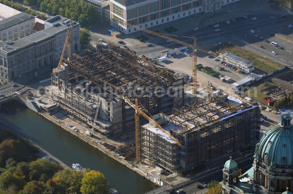 Berlin from the bird's eye view: Blick auf den Abriss des Palast der Republik in Mitte.Der Rückbau des Palastes der Republik verschob sich immer wieder. Am 19. Januar 2006 beschloss der Deutsche Bundestag, Anträgen der Grünen und der Linkspartei zur Verschiebung des Abrisses bzw. zur Erhaltung des Bauwerks nicht stattzugeben.Nach Terminen im Frühjahr 2005 und im Oktober 2005 wird das Gebäude seit Februar 2006 langsam mithilfe von fünf Kränen zurückgebaut. Von einer Sprengung des Gebäudes wurde abgesehen, weil Beschädigungen umliegender Gebäude durch den Auftrieb der Bodenwanne und das dadurch bedingte Absinken des Grundwasserspiegels befürchtet wurden. Stattdessen wird das abgetragene Material gemessen und im gleichen Maß dann mit Wasser versetzter Sand in die Bodenwanne geleitet. Die Abrissarbeiten sollten ursprünglich Mitte 2007 abgeschlossen sein. Nachdem im Laufe der Arbeiten an mehreren Stellen neues Asbest gefunden wurde und sich der Abriss dadurch stark verlangsamte, wird mit Ende 2008 als frühestes Ende kalkuliert. Die Zusatzkosten in Höhe von bislang 9,9 Mio. Euro muss der Bund übernehmen.Nach der vollständigen Abtragung soll vorübergehend eine Grünfläche über der verbleibenden Bodenwanne entstehen. Diskutiert wird auch eine Zwischennutzung der Fläche durch eine Kunsthalle.