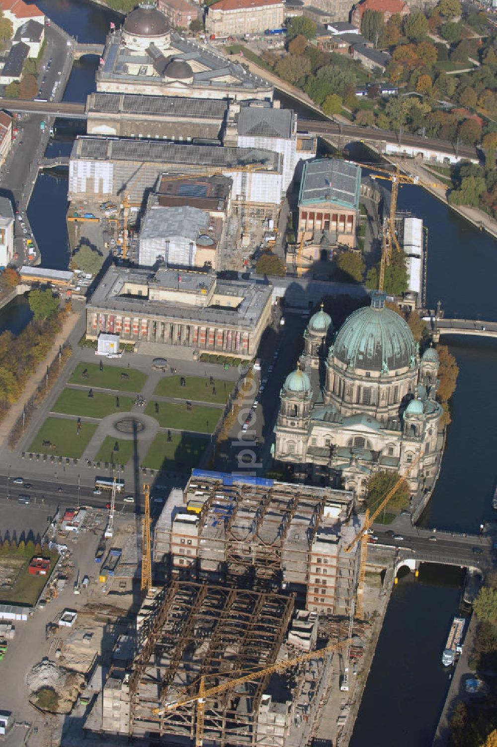 Aerial photograph Berlin - Blick auf den Abriss des Palast der Republik in Mitte.Der Rückbau des Palastes der Republik verschob sich immer wieder. Am 19. Januar 2006 beschloss der Deutsche Bundestag, Anträgen der Grünen und der Linkspartei zur Verschiebung des Abrisses bzw. zur Erhaltung des Bauwerks nicht stattzugeben.Nach Terminen im Frühjahr 2005 und im Oktober 2005 wird das Gebäude seit Februar 2006 langsam mithilfe von fünf Kränen zurückgebaut. Von einer Sprengung des Gebäudes wurde abgesehen, weil Beschädigungen umliegender Gebäude durch den Auftrieb der Bodenwanne und das dadurch bedingte Absinken des Grundwasserspiegels befürchtet wurden. Stattdessen wird das abgetragene Material gemessen und im gleichen Maß dann mit Wasser versetzter Sand in die Bodenwanne geleitet. Die Abrissarbeiten sollten ursprünglich Mitte 2007 abgeschlossen sein. Nachdem im Laufe der Arbeiten an mehreren Stellen neues Asbest gefunden wurde und sich der Abriss dadurch stark verlangsamte, wird mit Ende 2008 als frühestes Ende kalkuliert. Die Zusatzkosten in Höhe von bislang 9,9 Mio. Euro muss der Bund übernehmen.Nach der vollständigen Abtragung soll vorübergehend eine Grünfläche über der verbleibenden Bodenwanne entstehen. Diskutiert wird auch eine Zwischennutzung der Fläche durch eine Kunsthalle.