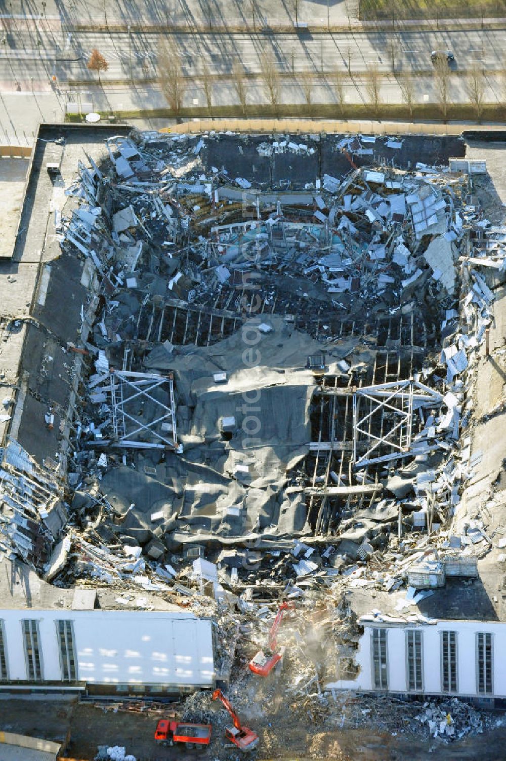 Aerial image Berlin - Blick auf die Abrißarbeiten an der ehemaligen Deutschlandhalle an der Jaffeystraße auf dem Messegelände in Charlottenburg. Abbruch-Bagger der Berliner Firma „ RWG1 “ setzten sie ihre tonnenschweren Kneifzangen in Betrieb und hackten sich in den Beton. Begonnen wurde mit dem Fassaden-Abriss an der Nordseite der Halle mit Abbruch-Bagger der Marke „ Liebherr “, Modelle 954 und 974. Sie wiegen 87 bis 140 Tonnen, haben bis zu 543 PS, nehmen die Fassade mit verschiedenen Greif- und Kneifbacken in die Zange. Der Abbruch soll bis März des Folgejahres beendet sein, um die nötige Baufreiheit für die Grundsteinlegung einer neuen Kongress- und Messehalle der Messe Berlin zu gewährleisten. Demolition work of the former Germany Halle Jaffeystraße on the fairgrounds in Charlottenburg.