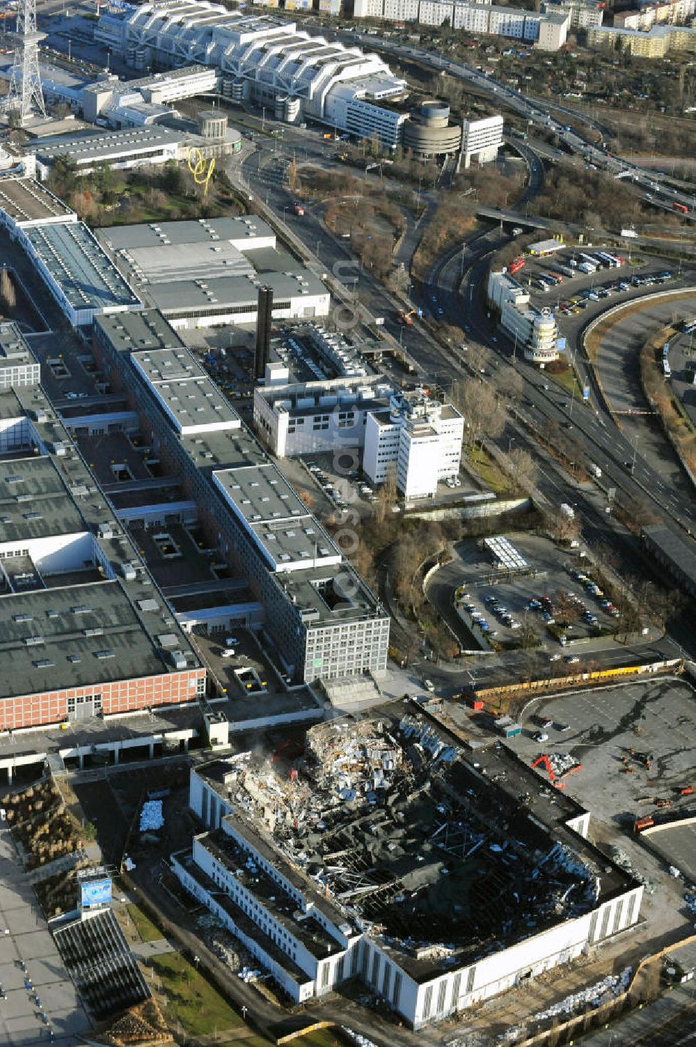 Berlin from the bird's eye view: Blick auf die Abrißarbeiten an der ehemaligen Deutschlandhalle an der Jaffeystraße auf dem Messegelände in Charlottenburg. Abbruch-Bagger der Berliner Firma „ RWG1 “ setzten sie ihre tonnenschweren Kneifzangen in Betrieb und hackten sich in den Beton. Begonnen wurde mit dem Fassaden-Abriss an der Nordseite der Halle mit Abbruch-Bagger der Marke „ Liebherr “, Modelle 954 und 974. Sie wiegen 87 bis 140 Tonnen, haben bis zu 543 PS, nehmen die Fassade mit verschiedenen Greif- und Kneifbacken in die Zange. Der Abbruch soll bis März des Folgejahres beendet sein, um die nötige Baufreiheit für die Grundsteinlegung einer neuen Kongress- und Messehalle der Messe Berlin zu gewährleisten. Demolition work of the former Germany Halle Jaffeystraße on the fairgrounds in Charlottenburg.