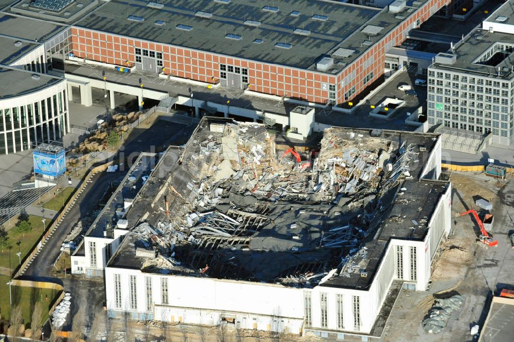 Berlin from above - Blick auf die Abrißarbeiten an der ehemaligen Deutschlandhalle an der Jaffeystraße auf dem Messegelände in Charlottenburg. Abbruch-Bagger der Berliner Firma „ RWG1 “ setzten sie ihre tonnenschweren Kneifzangen in Betrieb und hackten sich in den Beton. Begonnen wurde mit dem Fassaden-Abriss an der Nordseite der Halle mit Abbruch-Bagger der Marke „ Liebherr “, Modelle 954 und 974. Sie wiegen 87 bis 140 Tonnen, haben bis zu 543 PS, nehmen die Fassade mit verschiedenen Greif- und Kneifbacken in die Zange. Der Abbruch soll bis März des Folgejahres beendet sein, um die nötige Baufreiheit für die Grundsteinlegung einer neuen Kongress- und Messehalle der Messe Berlin zu gewährleisten. Demolition work of the former Germany Halle Jaffeystraße on the fairgrounds in Charlottenburg.