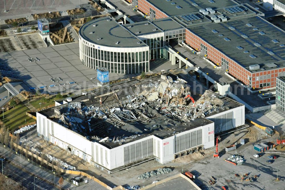 Berlin from the bird's eye view: Blick auf die Abrißarbeiten an der ehemaligen Deutschlandhalle an der Jaffeystraße auf dem Messegelände in Charlottenburg. Abbruch-Bagger der Berliner Firma „ RWG1 “ setzten sie ihre tonnenschweren Kneifzangen in Betrieb und hackten sich in den Beton. Begonnen wurde mit dem Fassaden-Abriss an der Nordseite der Halle mit Abbruch-Bagger der Marke „ Liebherr “, Modelle 954 und 974. Sie wiegen 87 bis 140 Tonnen, haben bis zu 543 PS, nehmen die Fassade mit verschiedenen Greif- und Kneifbacken in die Zange. Der Abbruch soll bis März des Folgejahres beendet sein, um die nötige Baufreiheit für die Grundsteinlegung einer neuen Kongress- und Messehalle der Messe Berlin zu gewährleisten. Demolition work of the former Germany Halle Jaffeystraße on the fairgrounds in Charlottenburg.