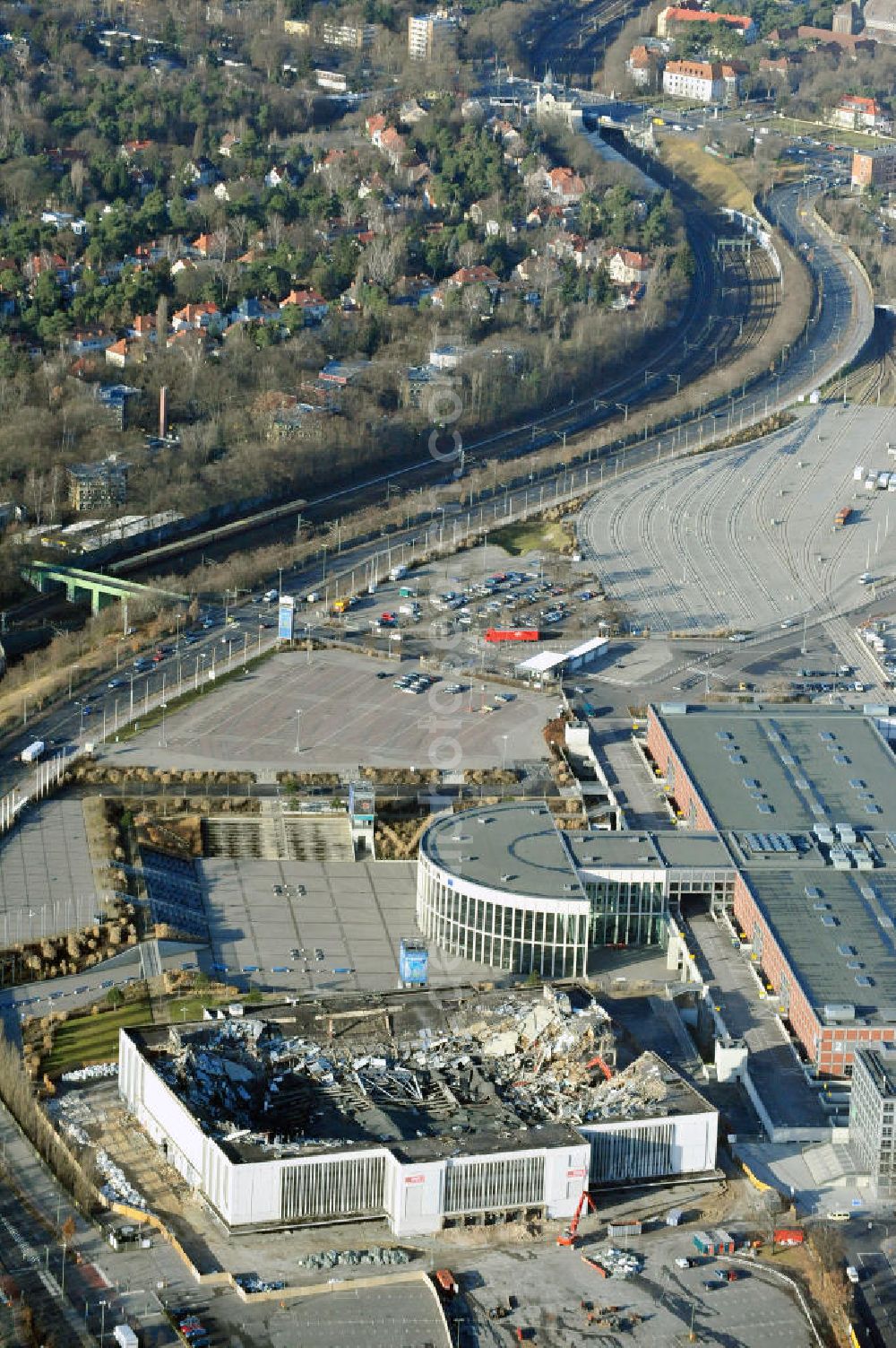 Aerial image Berlin - Blick auf die Abrißarbeiten an der ehemaligen Deutschlandhalle an der Jaffeystraße auf dem Messegelände in Charlottenburg. Abbruch-Bagger der Berliner Firma „ RWG1 “ setzten sie ihre tonnenschweren Kneifzangen in Betrieb und hackten sich in den Beton. Begonnen wurde mit dem Fassaden-Abriss an der Nordseite der Halle mit Abbruch-Bagger der Marke „ Liebherr “, Modelle 954 und 974. Sie wiegen 87 bis 140 Tonnen, haben bis zu 543 PS, nehmen die Fassade mit verschiedenen Greif- und Kneifbacken in die Zange. Der Abbruch soll bis März des Folgejahres beendet sein, um die nötige Baufreiheit für die Grundsteinlegung einer neuen Kongress- und Messehalle der Messe Berlin zu gewährleisten. Demolition work of the former Germany Halle Jaffeystraße on the fairgrounds in Charlottenburg.