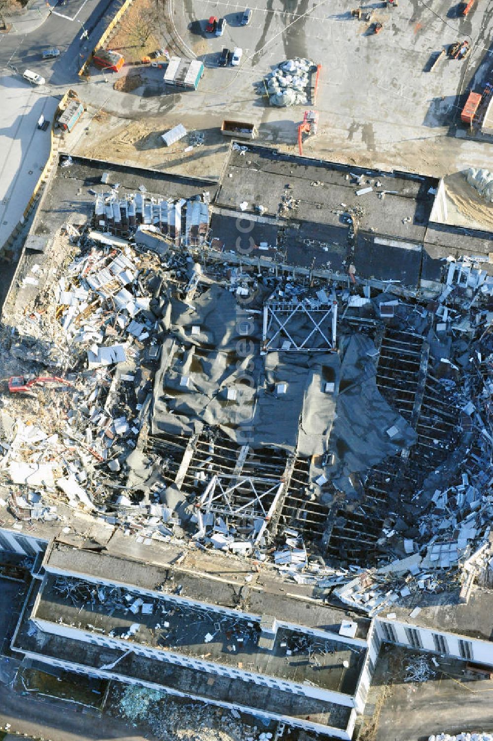 Aerial image Berlin - Blick auf die Abrißarbeiten an der ehemaligen Deutschlandhalle an der Jaffeystraße auf dem Messegelände in Charlottenburg. Abbruch-Bagger der Berliner Firma „ RWG1 “ setzten sie ihre tonnenschweren Kneifzangen in Betrieb und hackten sich in den Beton. Begonnen wurde mit dem Fassaden-Abriss an der Nordseite der Halle mit Abbruch-Bagger der Marke „ Liebherr “, Modelle 954 und 974. Sie wiegen 87 bis 140 Tonnen, haben bis zu 543 PS, nehmen die Fassade mit verschiedenen Greif- und Kneifbacken in die Zange. Der Abbruch soll bis März des Folgejahres beendet sein, um die nötige Baufreiheit für die Grundsteinlegung einer neuen Kongress- und Messehalle der Messe Berlin zu gewährleisten. Demolition work of the former Germany Halle Jaffeystraße on the fairgrounds in Charlottenburg.