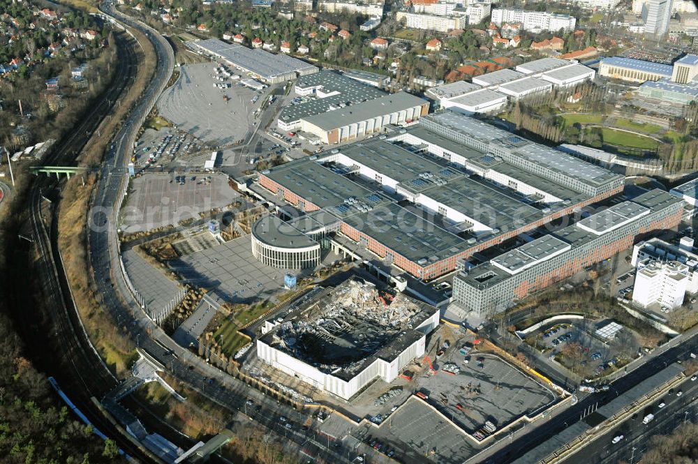 Aerial image Berlin - Blick auf die Abrißarbeiten an der ehemaligen Deutschlandhalle an der Jaffeystraße auf dem Messegelände in Charlottenburg. Abbruch-Bagger der Berliner Firma „ RWG1 “ setzten sie ihre tonnenschweren Kneifzangen in Betrieb und hackten sich in den Beton. Begonnen wurde mit dem Fassaden-Abriss an der Nordseite der Halle mit Abbruch-Bagger der Marke „ Liebherr “, Modelle 954 und 974. Sie wiegen 87 bis 140 Tonnen, haben bis zu 543 PS, nehmen die Fassade mit verschiedenen Greif- und Kneifbacken in die Zange. Der Abbruch soll bis März des Folgejahres beendet sein, um die nötige Baufreiheit für die Grundsteinlegung einer neuen Kongress- und Messehalle der Messe Berlin zu gewährleisten. Demolition work of the former Germany Halle Jaffeystraße on the fairgrounds in Charlottenburg.