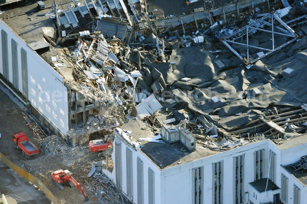 Aerial photograph Berlin - Blick auf die Abrißarbeiten an der ehemaligen Deutschlandhalle an der Jaffeystraße auf dem Messegelände in Charlottenburg. Abbruch-Bagger der Berliner Firma „ RWG1 “ setzten sie ihre tonnenschweren Kneifzangen in Betrieb und hackten sich in den Beton. Begonnen wurde mit dem Fassaden-Abriss an der Nordseite der Halle mit Abbruch-Bagger der Marke „ Liebherr “, Modelle 954 und 974. Sie wiegen 87 bis 140 Tonnen, haben bis zu 543 PS, nehmen die Fassade mit verschiedenen Greif- und Kneifbacken in die Zange. Der Abbruch soll bis März des Folgejahres beendet sein, um die nötige Baufreiheit für die Grundsteinlegung einer neuen Kongress- und Messehalle der Messe Berlin zu gewährleisten. Demolition work of the former Germany Halle Jaffeystraße on the fairgrounds in Charlottenburg.