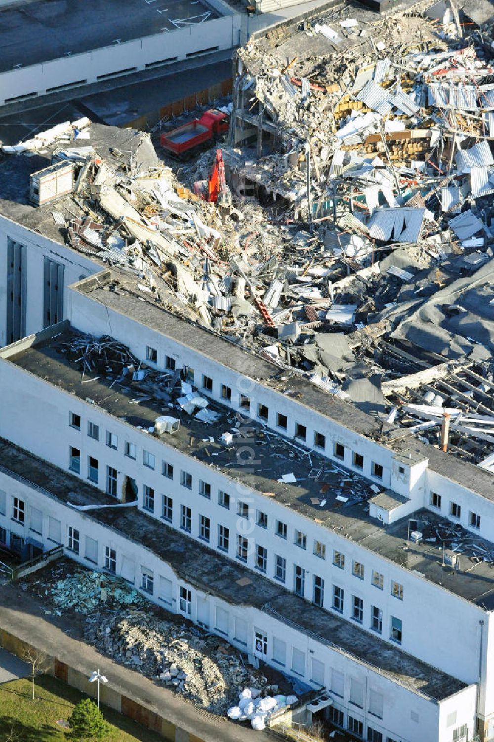 Aerial image Berlin - Blick auf die Abrißarbeiten an der ehemaligen Deutschlandhalle an der Jaffeystraße auf dem Messegelände in Charlottenburg. Abbruch-Bagger der Berliner Firma „ RWG1 “ setzten sie ihre tonnenschweren Kneifzangen in Betrieb und hackten sich in den Beton. Begonnen wurde mit dem Fassaden-Abriss an der Nordseite der Halle mit Abbruch-Bagger der Marke „ Liebherr “, Modelle 954 und 974. Sie wiegen 87 bis 140 Tonnen, haben bis zu 543 PS, nehmen die Fassade mit verschiedenen Greif- und Kneifbacken in die Zange. Der Abbruch soll bis März des Folgejahres beendet sein, um die nötige Baufreiheit für die Grundsteinlegung einer neuen Kongress- und Messehalle der Messe Berlin zu gewährleisten. Demolition work of the former Germany Halle Jaffeystraße on the fairgrounds in Charlottenburg.