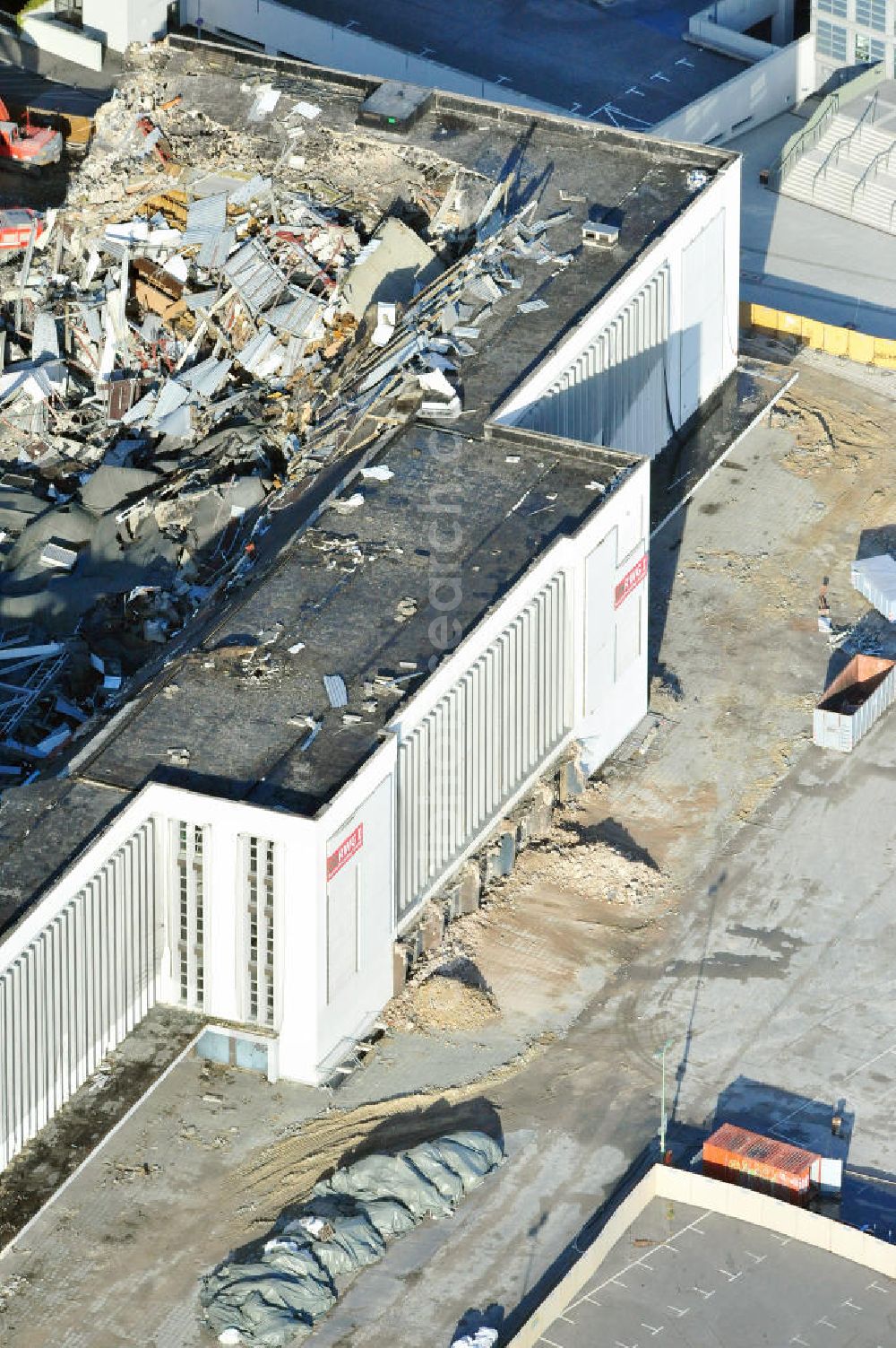 Aerial photograph Berlin - Blick auf die Abrißarbeiten an der ehemaligen Deutschlandhalle an der Jaffeystraße auf dem Messegelände in Charlottenburg. Abbruch-Bagger der Berliner Firma „ RWG1 “ setzten sie ihre tonnenschweren Kneifzangen in Betrieb und hackten sich in den Beton. Begonnen wurde mit dem Fassaden-Abriss an der Nordseite der Halle mit Abbruch-Bagger der Marke „ Liebherr “, Modelle 954 und 974. Sie wiegen 87 bis 140 Tonnen, haben bis zu 543 PS, nehmen die Fassade mit verschiedenen Greif- und Kneifbacken in die Zange. Der Abbruch soll bis März des Folgejahres beendet sein, um die nötige Baufreiheit für die Grundsteinlegung einer neuen Kongress- und Messehalle der Messe Berlin zu gewährleisten. Demolition work of the former Germany Halle Jaffeystraße on the fairgrounds in Charlottenburg.