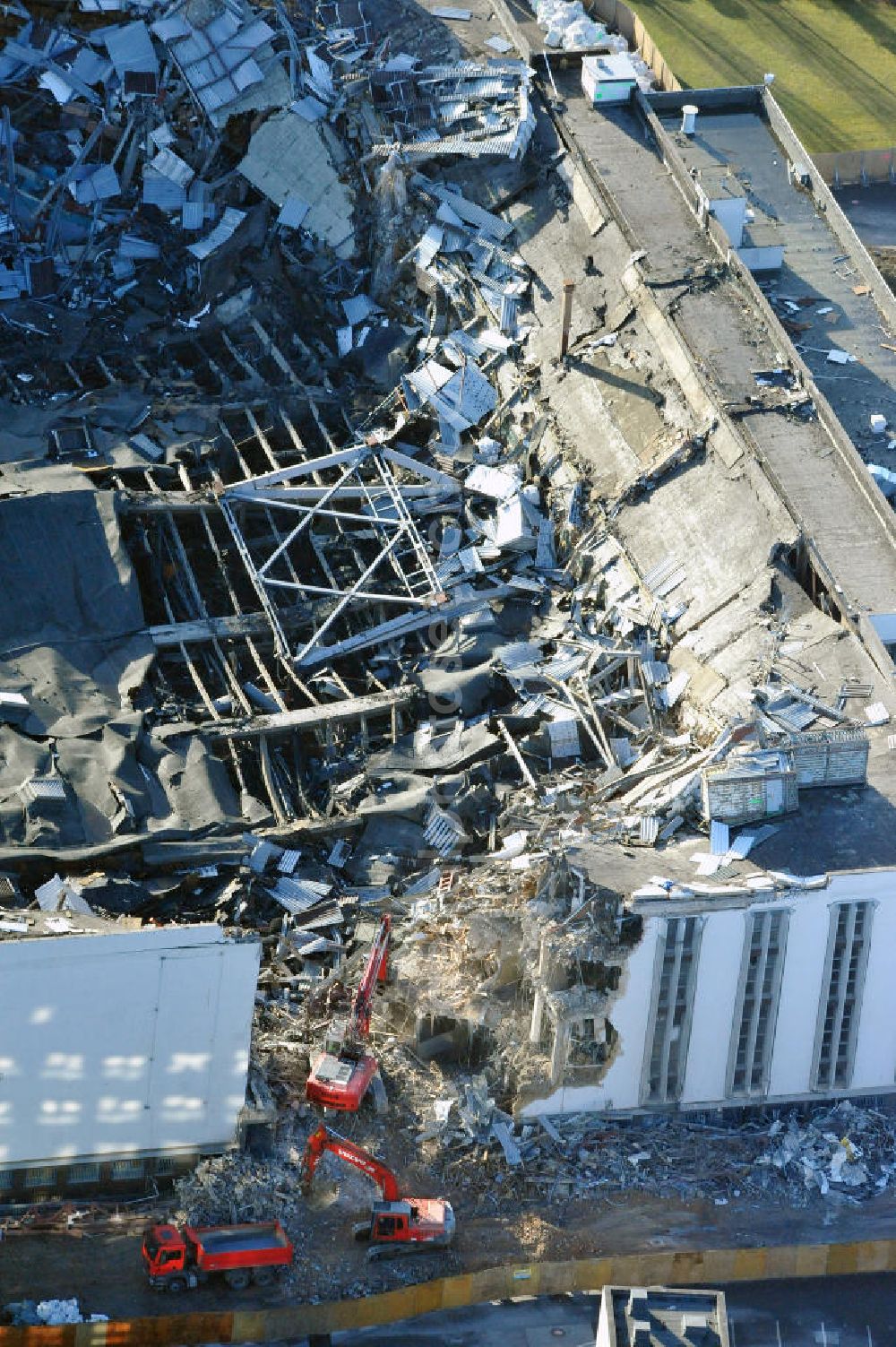 Aerial photograph Berlin - Blick auf die Abrißarbeiten an der ehemaligen Deutschlandhalle an der Jaffeystraße auf dem Messegelände in Charlottenburg. Abbruch-Bagger der Berliner Firma „ RWG1 “ setzten sie ihre tonnenschweren Kneifzangen in Betrieb und hackten sich in den Beton. Begonnen wurde mit dem Fassaden-Abriss an der Nordseite der Halle mit Abbruch-Bagger der Marke „ Liebherr “, Modelle 954 und 974. Sie wiegen 87 bis 140 Tonnen, haben bis zu 543 PS, nehmen die Fassade mit verschiedenen Greif- und Kneifbacken in die Zange. Der Abbruch soll bis März des Folgejahres beendet sein, um die nötige Baufreiheit für die Grundsteinlegung einer neuen Kongress- und Messehalle der Messe Berlin zu gewährleisten. Demolition work of the former Germany Halle Jaffeystraße on the fairgrounds in Charlottenburg.