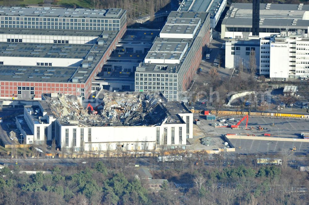 Berlin from above - Blick auf die Abrißarbeiten an der ehemaligen Deutschlandhalle an der Jaffeystraße auf dem Messegelände in Charlottenburg. Abbruch-Bagger der Berliner Firma „ RWG1 “ setzten sie ihre tonnenschweren Kneifzangen in Betrieb und hackten sich in den Beton. Begonnen wurde mit dem Fassaden-Abriss an der Nordseite der Halle mit Abbruch-Bagger der Marke „ Liebherr “, Modelle 954 und 974. Sie wiegen 87 bis 140 Tonnen, haben bis zu 543 PS, nehmen die Fassade mit verschiedenen Greif- und Kneifbacken in die Zange. Der Abbruch soll bis März des Folgejahres beendet sein, um die nötige Baufreiheit für die Grundsteinlegung einer neuen Kongress- und Messehalle der Messe Berlin zu gewährleisten. Demolition work of the former Germany Halle Jaffeystraße on the fairgrounds in Charlottenburg.