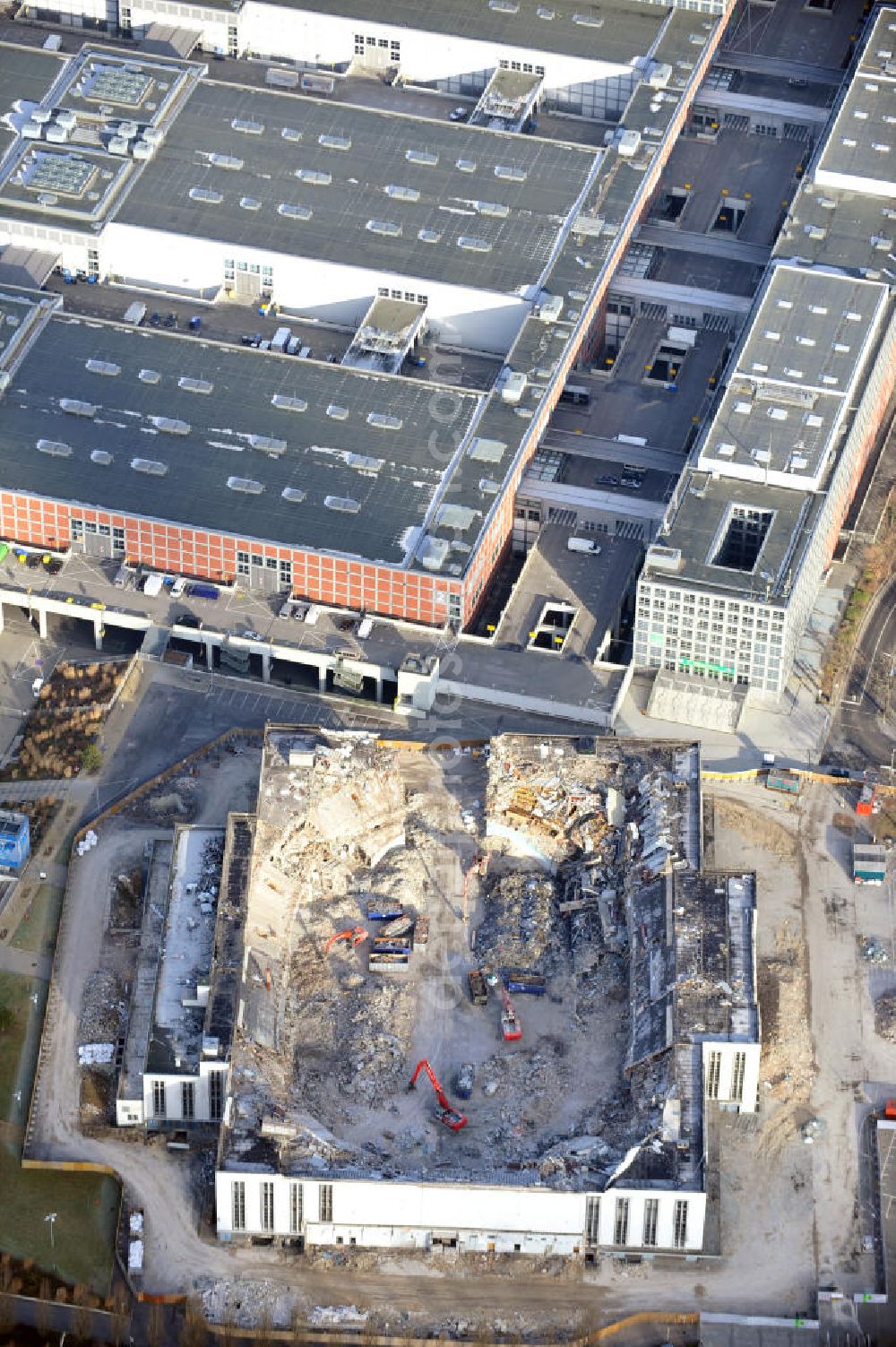 Berlin from the bird's eye view: Blick auf die Abrißarbeiten an der ehemaligen Deutschlandhalle an der Jaffeystraße auf dem Messegelände in Charlottenburg. Abbruch-Bagger der Berliner Firma „ RWG1 “ setzten sie ihre tonnenschweren Kneifzangen in Betrieb und hackten sich in den Beton. Begonnen wurde mit dem Fassaden-Abriss an der Nordseite der Halle mit Abbruch-Bagger der Marke „ Liebherr “, Modelle 954 und 974. Sie wiegen 87 bis 140 Tonnen, haben bis zu 543 PS, nehmen die Fassade mit verschiedenen Greif- und Kneifbacken in die Zange. Der Abbruch soll bis März des Folgejahres beendet sein, um die nötige Baufreiheit für die Grundsteinlegung einer neuen Kongress- und Messehalle der Messe Berlin zu gewährleisten. Demolition work of the former Germany Halle Jaffeystraße on the fairgrounds in Charlottenburg.