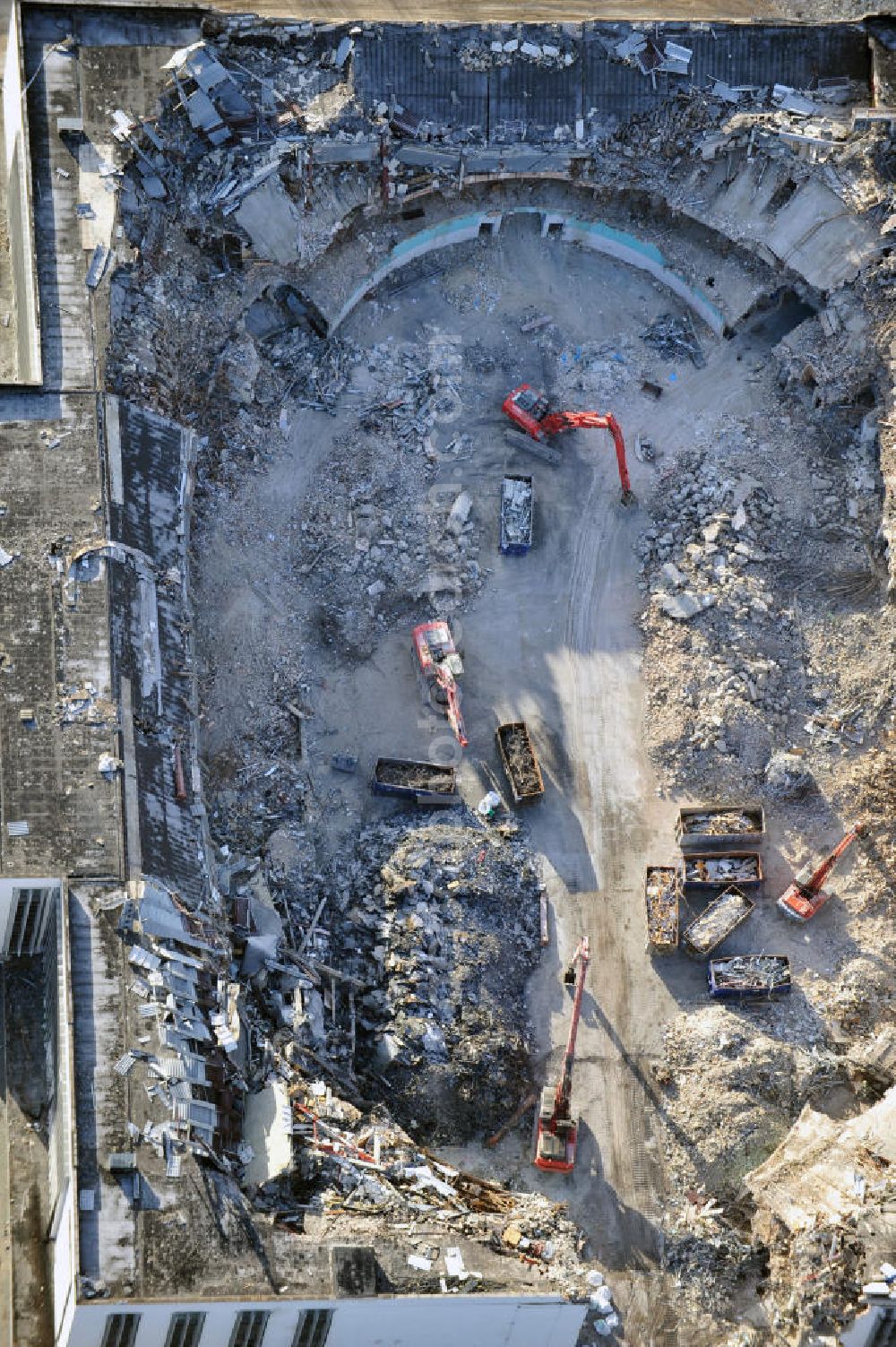 Berlin from the bird's eye view: Blick auf die Abrißarbeiten an der ehemaligen Deutschlandhalle an der Jaffeystraße auf dem Messegelände in Charlottenburg. Abbruch-Bagger der Berliner Firma „ RWG1 “ setzten sie ihre tonnenschweren Kneifzangen in Betrieb und hackten sich in den Beton. Begonnen wurde mit dem Fassaden-Abriss an der Nordseite der Halle mit Abbruch-Bagger der Marke „ Liebherr “, Modelle 954 und 974. Sie wiegen 87 bis 140 Tonnen, haben bis zu 543 PS, nehmen die Fassade mit verschiedenen Greif- und Kneifbacken in die Zange. Der Abbruch soll bis März des Folgejahres beendet sein, um die nötige Baufreiheit für die Grundsteinlegung einer neuen Kongress- und Messehalle der Messe Berlin zu gewährleisten. Demolition work of the former Germany Halle Jaffeystraße on the fairgrounds in Charlottenburg.