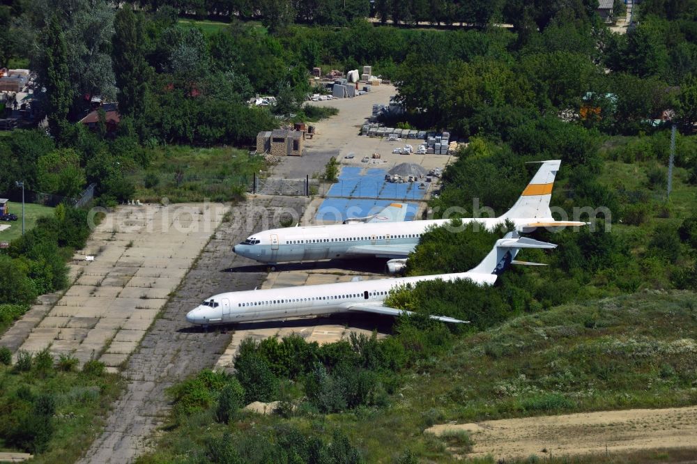 Bukarest from the bird's eye view: Old airplanes on Baneasa International Airport. The airliners are standing between trees and greens at the airport's western end. The airport is located in the industrial and commercial area of the city