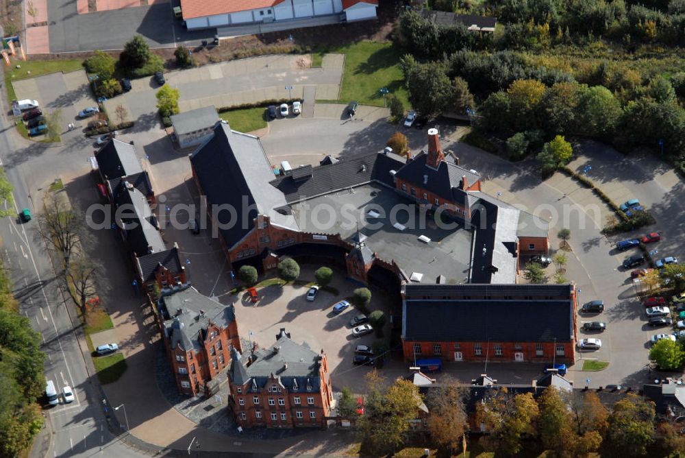 Aerial image Gotha - Auf dem ca. 23.870 m² große Grundstück befindet sich ein Einzeldenkmal, erbaut im Jahre 1890-1891 vom Architekten Conrad Schaller. Das ehemals als Schlachthof genutzte Gebäudeensemble wurde in den Jahren 1993/1994 zu einem multifunktionalen Zentrum mit Handels- und Dienstleistungseinrichtungen umgebaut. Das eigentliche Schlachthaus wurde in Absprache mit dem Denkmalschutz und nach Renovierung der Altfassade als Geschäftscenter mit Klein- und Großläden umgebaut. Die ehemaligen Stallungsgebäude entlang der Parkstraße und der Ülleber Straße wurden nach Teilabrissen, nachträglichen An- und Ausbauten und Fassadenrenovierungen zu Kleinladenzeilen umgebaut. Das alte Schlachthof-Gelände liegt westlich des Stadtzentrums - unweit vom Schlosspark und ist eine der architektonisch attraktivsten Straßenzüge in Gotha.