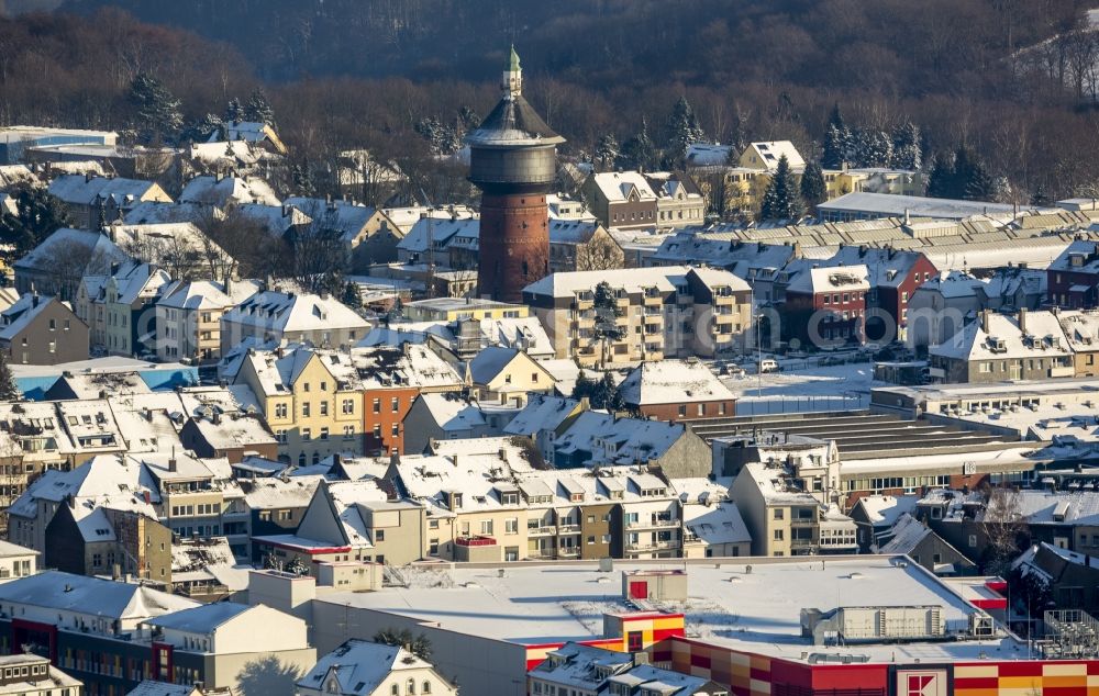 Velbert from above - Old Water Tower and cityscape of the winterly and snow-covered Velbert in the state of North Rhine-Westphalia. The red brick tower with its green top and the onion-shaped dome is located on Steeger Strasse in the East of the historic town centre of Velbert which includes several historic buildings. The tower was built in 1904 and is listed as a protected building