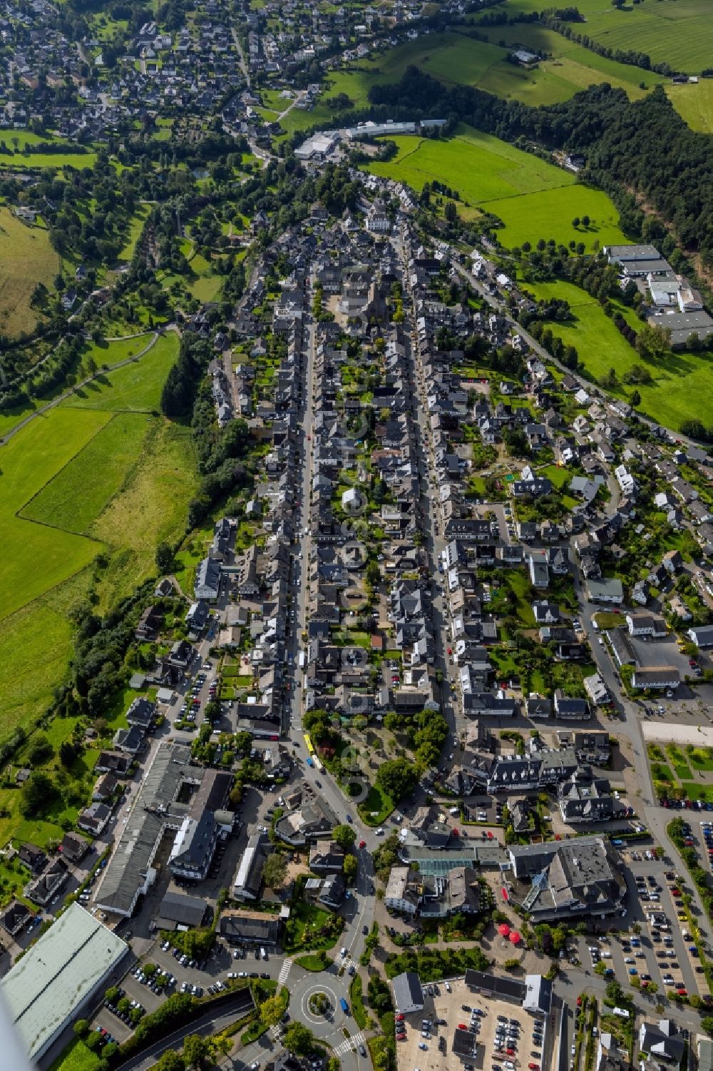 Aerial photograph Schmallenberg - View of the course of the streets Oststrasse and Weststrasse through the historical city centre of Schmallenberg in the state North Rhine-Westphalia. They are lined with grey houses and at the end of the street the church St.-Alexan der is visible