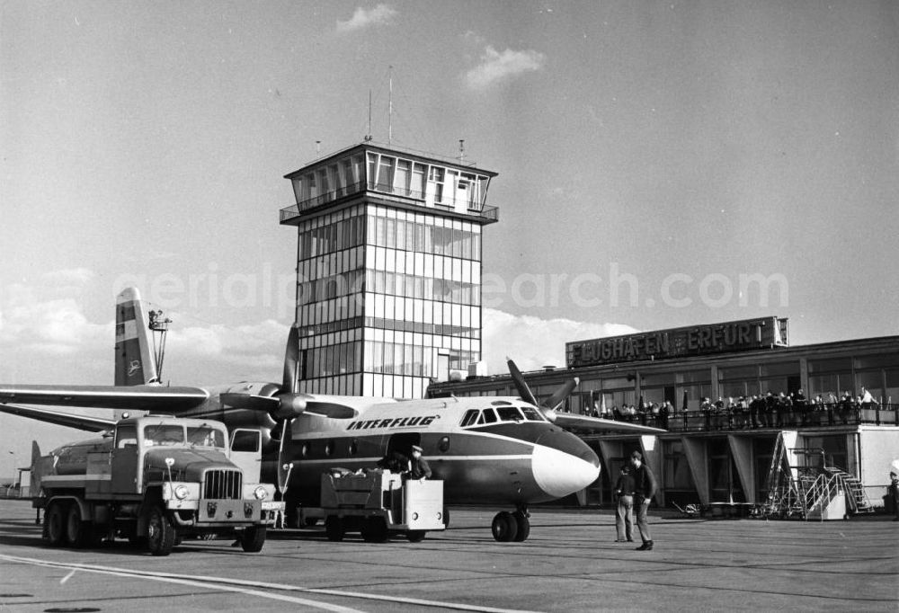 Erfurt from above - Blick auf das Vorfeld vom Flughafen Erfurt mit Tower / Turm und Abfertigungsgebäude im Hintergrund. Flugvorbereitungen an einer Antonow An-24 Passagiermaschine der Interflug, Tankwagen sowie Gepäckwagen stehen neben der An-24.