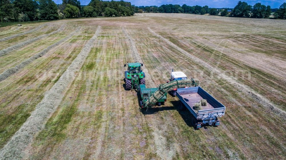 Aerial photograph Planetal - Working hay harvest with harvesters on agricultural field rows in Planetal in the state Brandenburg, Germany