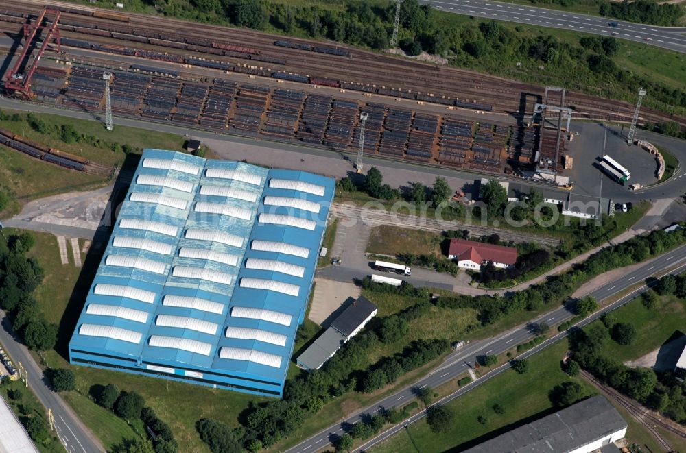 Aerial image Unterwellenborn - At the Kronacher Street in Unterwellenborn in Thuringia, the company Arcelor Mittal steel trade has an establishment. By means of the crane system are reloaded steel profiles from the neighboring steel mill on standing by freight trains. The steel trade has extensive railway sidings