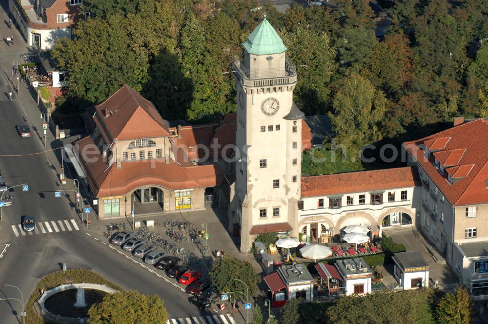 Aerial image Berlin - Frohnau - Blick auf den das Areal am S-Bahnhof Berlin - Frohnau am Ludolfingerplatz , Frohnauer Brücke. Der Casinoturm wurde zwischen 1909 und 1910 als 30 Meter hohes Wahrzeichen des Ortsteils nach einem Entwurf der Architekten Gustav Hart und Alfred Lesser erbaut. Der balkonartige Umgang unterhalb der Turmspitze in einer Höhe von 26,5 Metern ist als Aussichtsplattform gestaltet. Das Bahnhofsgebäude mit dem tief gelegenen Bahnsteig ließ die Eisenbahndirektion Berlin 1908–1910 ebenfalls nach einem Entwurf der Architektengemeinschaft Gustav Hart & Alfred Lesser errichten. Beim Bau der Berliner Mauer 1961 wurde die S-Bahn zwischen den Bahnhöfen Frohnau und Hohen Neuendorf stillgelegt und erst am 31. Mai 1992 wieder eröffnet.