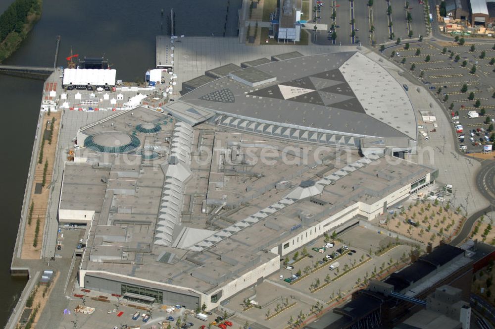 BREMEN from the bird's eye view: Areal des Space Parks Bremen. Das Projekt wurde Anfang der 1990er Jahre von der in Wiesbaden ansässigen, inzwischen nicht mehr existenten Köllmann AG zusammen mit dem noch nicht realisierten Ocean Park in Bremerhaven geplant. Der Kerngedanke ist dabei die für Urban Entertainment Center typische Verbindung von Unterhaltung und Einzelhandel. Das Projekt wurde mit Unterstützung des Landes Bremen in Form von Subventionen unter Bauherrenschaft der zur Dresdner Bank gehörenden DEGI realisiert. Der Bau wurde im Juli 2000 begonnen und war am 19. Dezember 2003 fertig gestellt. Eröffnet wurde der Park am 12. Februar 2004.Der Space Park wurde an die britische Finanzinvestorengruppe „Cardinal Asset Management“ verkauft. Diese erklärte von Beginn an, den Space Park nicht selbst betreiben zu wollen, und verkaufte ihn schließlich für 50 Millionen Euro an den irischen Finanzdienstleister LNC Property Group. Im Februar 2007 kündigte der LNC-Chef Bill McCabe an, dass die LNC weitere 80 bis 100 Millionen Euro investieren wolle, um das Areal baulich zur Weser hin auszurichten und den Einzelhandelsbereich des Space Parks unter dem Namen „Waterfront Bremen“ im September 2008 wiederzueröffnen. Bis 2009 soll ein Sport-, Freizeit- und Wellnessbereich hinzukommen. Kalkuliert ist ein Einzugsgebiet mit einem Durchmesser von 200 Kilometern und eine Besucherzahl von im Durchschnitt täglich 25.000 Besuchern. Im Frühjahr 2007 wurde das Space Park Logo entfernt. Seit Anfang August hängt der Name Waterfront am Eingang. Limetree GmbH, AG-Weser-Straße 3 , 28237 Bremen,Telefon: +49 4213305 300;