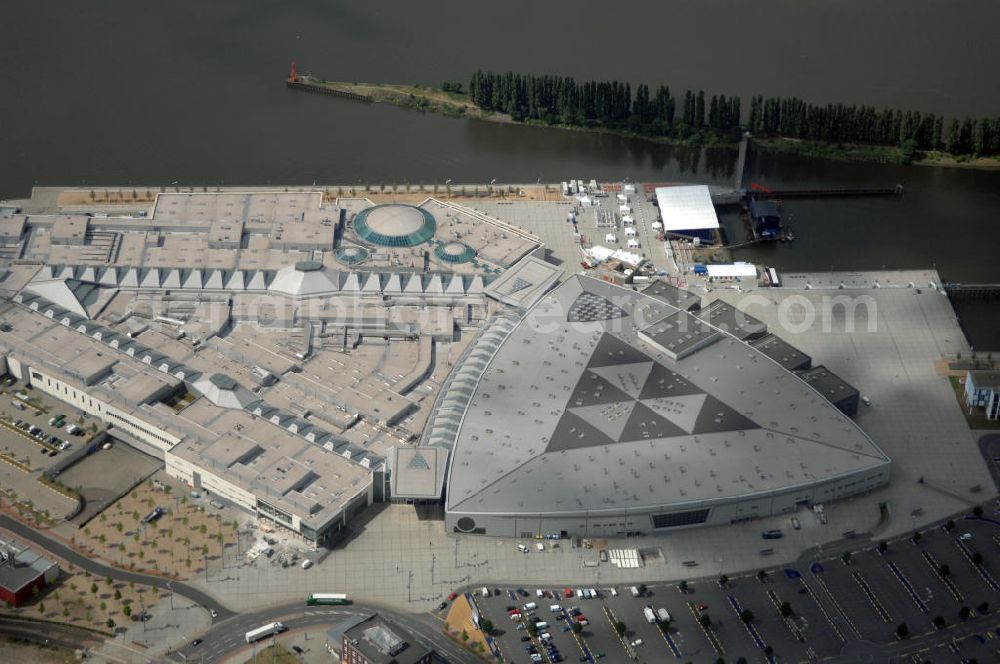 Aerial photograph BREMEN - Areal des Space Parks Bremen. Das Projekt wurde Anfang der 1990er Jahre von der in Wiesbaden ansässigen, inzwischen nicht mehr existenten Köllmann AG zusammen mit dem noch nicht realisierten Ocean Park in Bremerhaven geplant. Der Kerngedanke ist dabei die für Urban Entertainment Center typische Verbindung von Unterhaltung und Einzelhandel. Das Projekt wurde mit Unterstützung des Landes Bremen in Form von Subventionen unter Bauherrenschaft der zur Dresdner Bank gehörenden DEGI realisiert. Der Bau wurde im Juli 2000 begonnen und war am 19. Dezember 2003 fertig gestellt. Eröffnet wurde der Park am 12. Februar 2004.Der Space Park wurde an die britische Finanzinvestorengruppe „Cardinal Asset Management“ verkauft. Diese erklärte von Beginn an, den Space Park nicht selbst betreiben zu wollen, und verkaufte ihn schließlich für 50 Millionen Euro an den irischen Finanzdienstleister LNC Property Group. Im Februar 2007 kündigte der LNC-Chef Bill McCabe an, dass die LNC weitere 80 bis 100 Millionen Euro investieren wolle, um das Areal baulich zur Weser hin auszurichten und den Einzelhandelsbereich des Space Parks unter dem Namen „Waterfront Bremen“ im September 2008 wiederzueröffnen. Bis 2009 soll ein Sport-, Freizeit- und Wellnessbereich hinzukommen. Kalkuliert ist ein Einzugsgebiet mit einem Durchmesser von 200 Kilometern und eine Besucherzahl von im Durchschnitt täglich 25.000 Besuchern. Im Frühjahr 2007 wurde das Space Park Logo entfernt. Seit Anfang August hängt der Name Waterfront am Eingang. Limetree GmbH, AG-Weser-Straße 3 , 28237 Bremen,Telefon: +49 4213305 300;