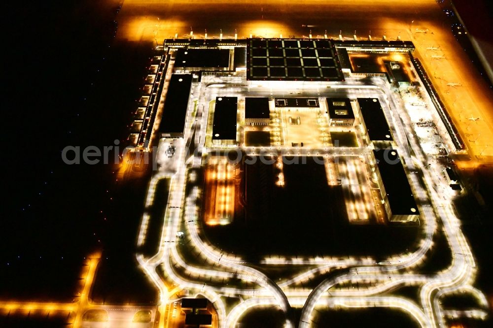 Schönefeld at night from the bird perspective: Night lighting dispatch building and terminals on the premises of the airport BER in Schoenefeld in the state Brandenburg