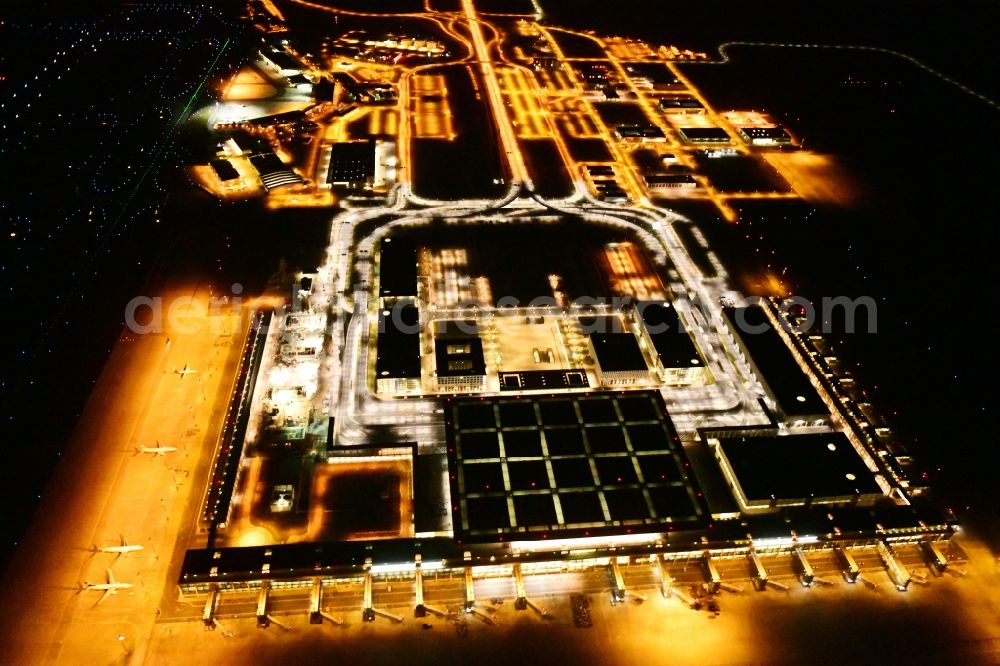 Schönefeld at night from the bird perspective: Night lighting dispatch building and terminals on the premises of the airport BER in Schoenefeld in the state Brandenburg