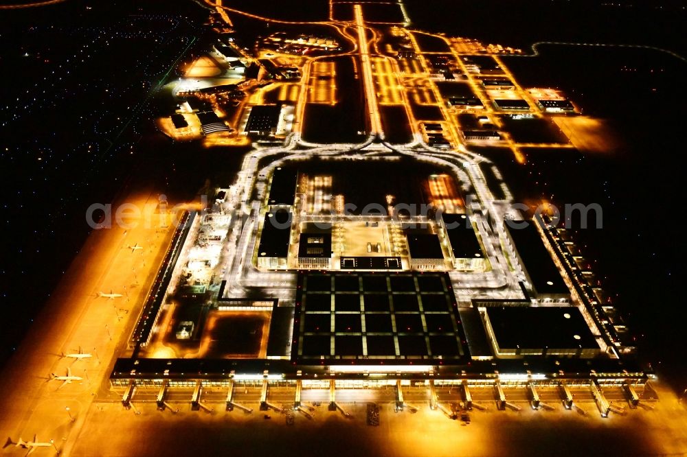 Aerial photograph at night Schönefeld - Night lighting dispatch building and terminals on the premises of the airport BER in Schoenefeld in the state Brandenburg