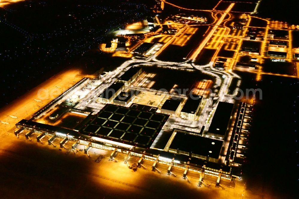 Schönefeld at night from the bird perspective: Night lighting dispatch building and terminals on the premises of the airport BER in Schoenefeld in the state Brandenburg