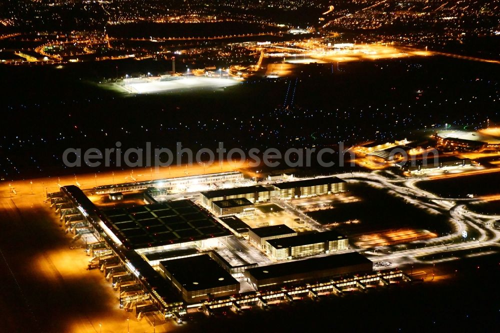 Schönefeld at night from the bird perspective: Night lighting dispatch building and terminals on the premises of the airport BER in Schoenefeld in the state Brandenburg