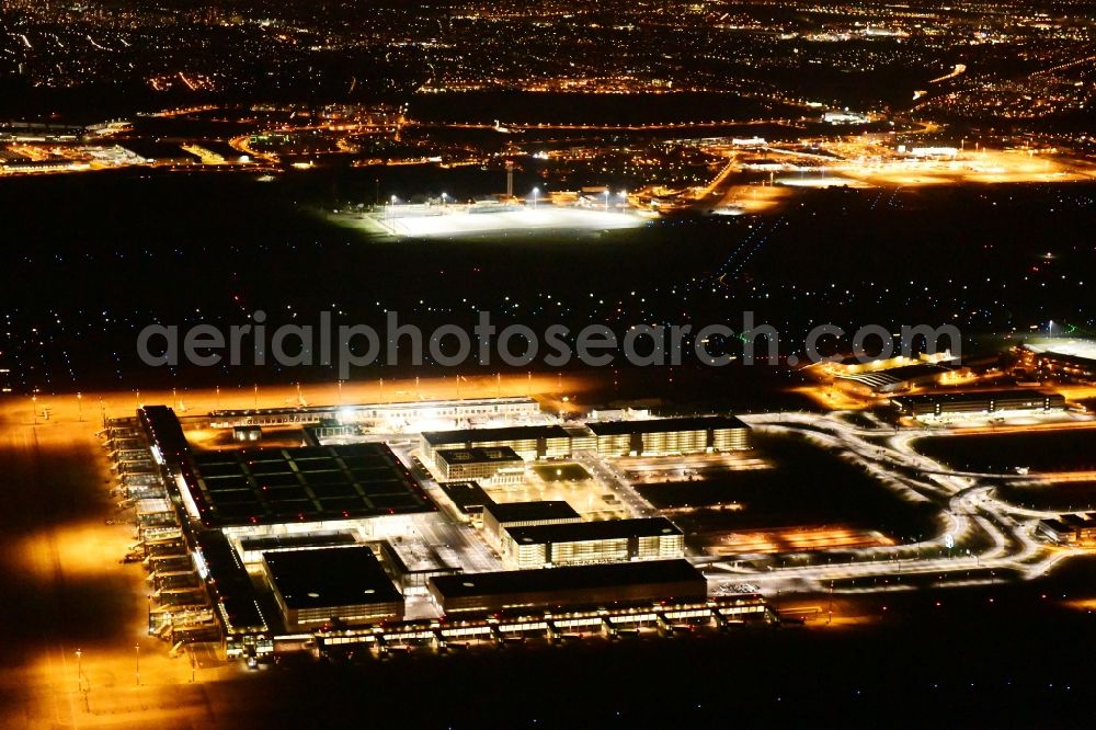 Aerial photograph at night Schönefeld - Night lighting dispatch building and terminals on the premises of the airport BER in Schoenefeld in the state Brandenburg