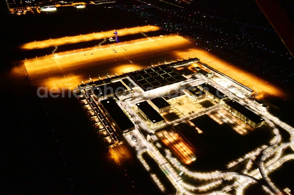 Aerial image at night Schönefeld - Night lighting dispatch building and terminals on the premises of the airport BER in Schoenefeld in the state Brandenburg