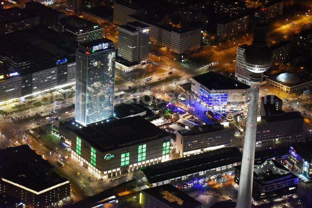 Berlin at night from the bird perspective: Night view overlooking illuminated buildings at Alexanderplatz in the center of Berlin. Visible among others are the shopping centre Galeria Kaufhof as well as the Park Inn Hotel and the television tower